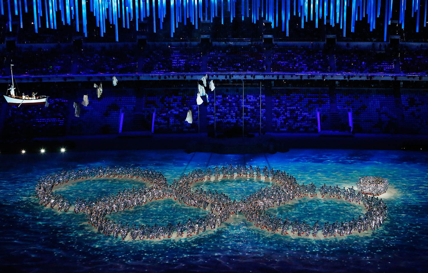 Dancers create the incomplete Olympic Rings.