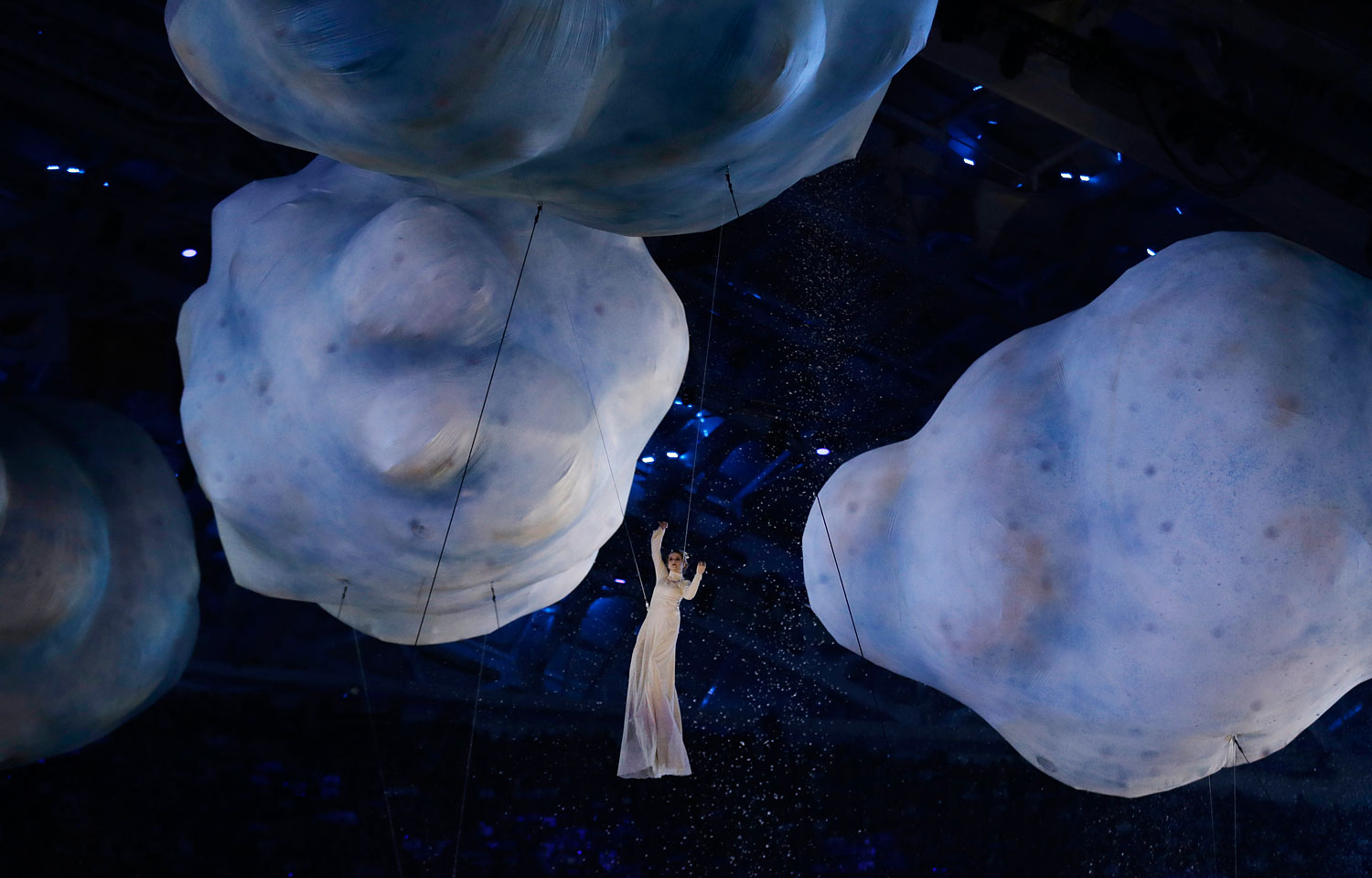 A performer is suspended from helium-filled clouds.