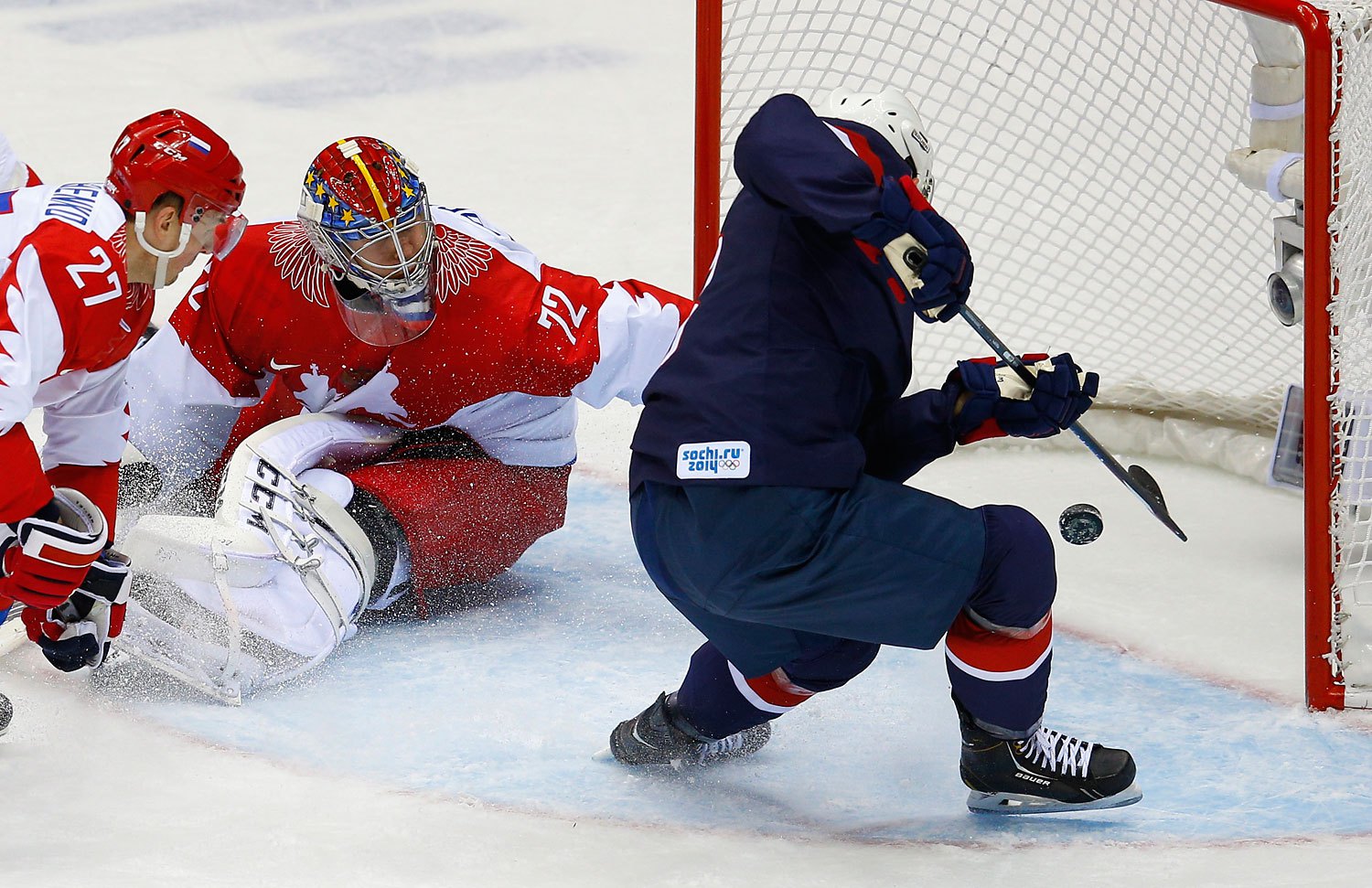 Team USA's Cam Fowler, right, scores on Russia's goalie Sergei Bobrovski and Russia's Alexei Tereshenko during the second period of their men's preliminary round ice hockey game.