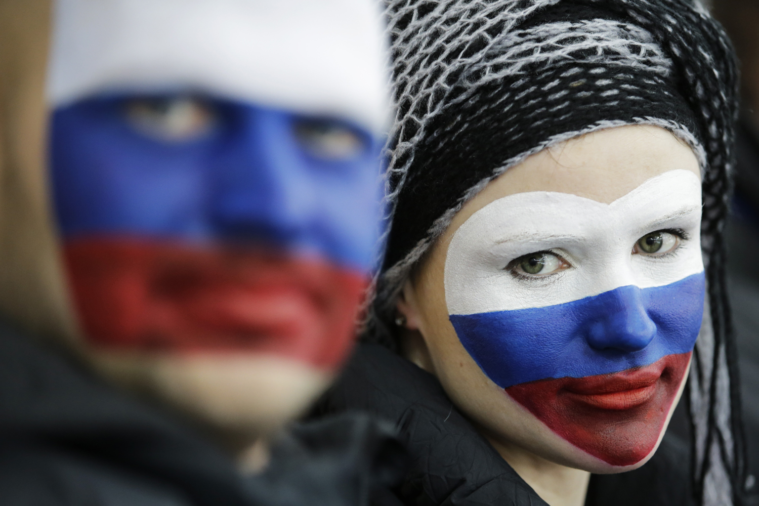 Russian skating fans, faces painted with the colors of their national flag, wait for the start of the women's 1,500-meter speedskating race at the Adler Arena Skating Center during the 2014 Winter Olympics, Sunday, Feb. 16, 2014, in Sochi, Russia.
