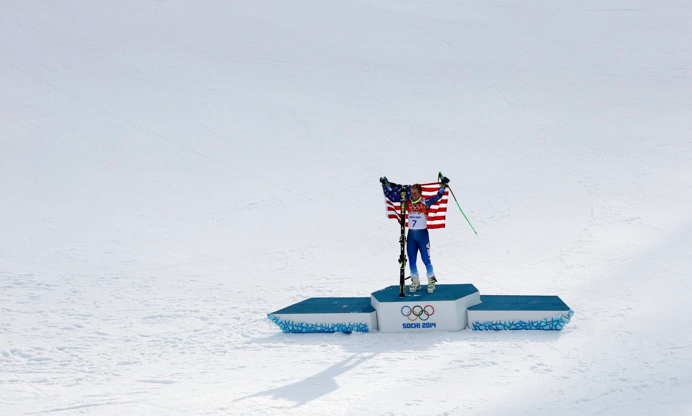 Winner Ted Ligety of the U.S. holds up his flag on the podium after the men's alpine skiing giant slalom event.