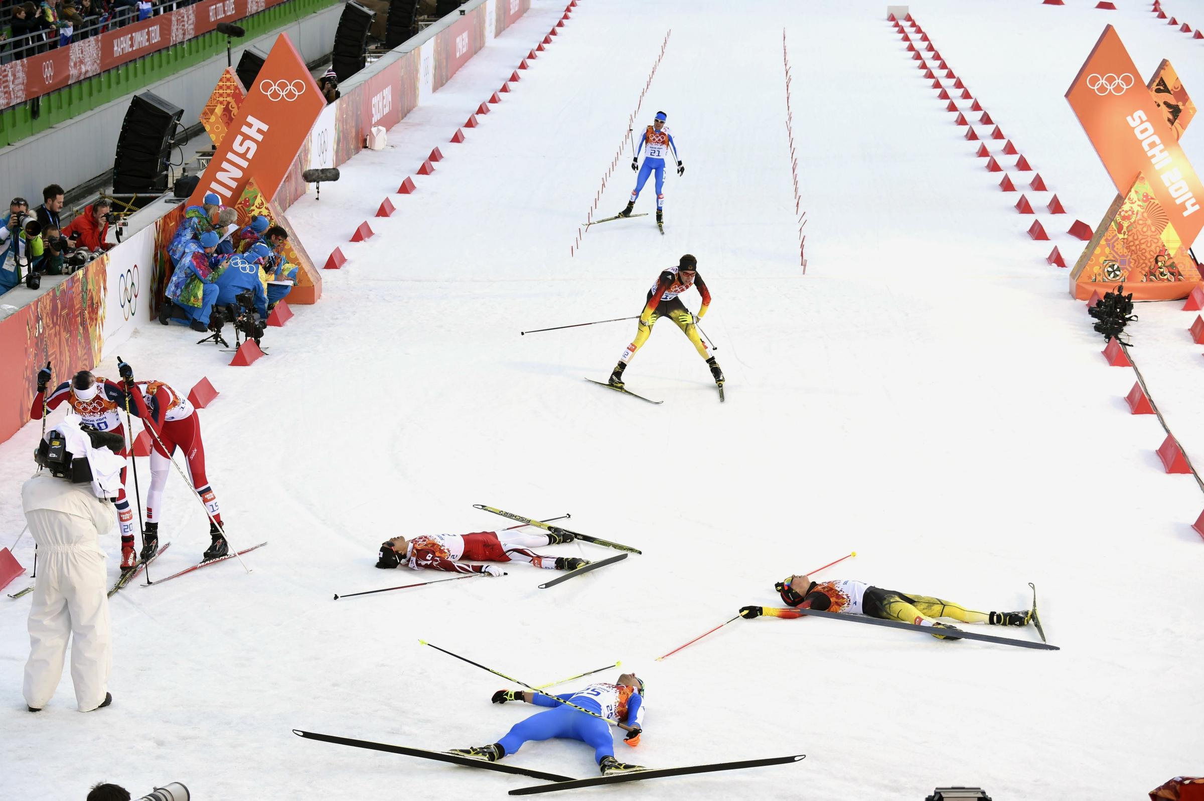 Gold medalist Germany's Eric Frenzel, silver medalist Japan's Akito Watabe and fourth place Italy's Alessandro Pittin lie on the snow at the finish line of the Nordic Combined Individual NH / 10 km Cross-Country.