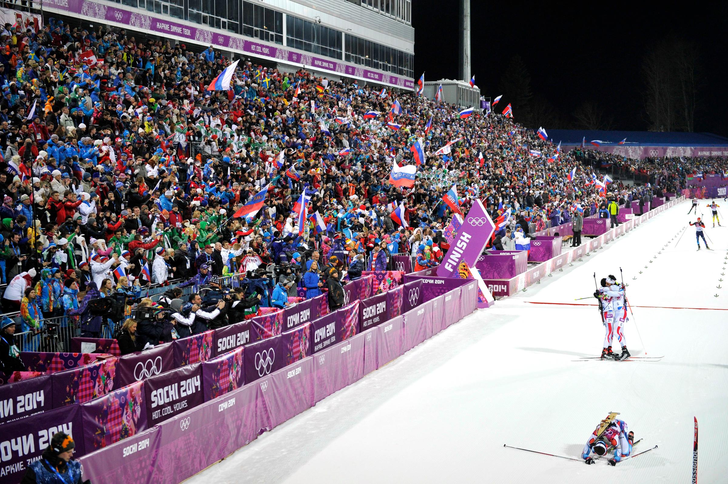 Gold medalist Martin Fourcade and bronze medalist Jean Guillaume Beatrix, both of France, celebrate while silver medalist Ondrej Moravec of the Czech Republic lies on the ground in the finish area of the Biathlon Men's 12.5km Pursuit at the Laura Cross-country Ski &amp; Biathlon Center.