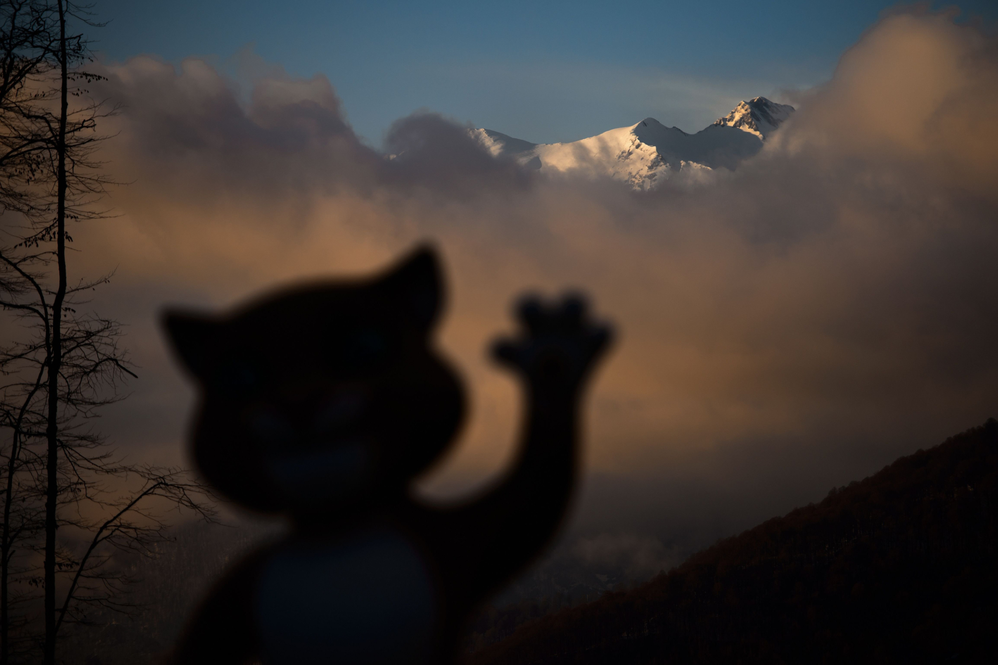 A mascot of Sochi Winter Olympics is seen in silhouette with mountains at sunset at the Mountain athletes village during the Sochi Winter Olympics on Feb. 11, 2014.