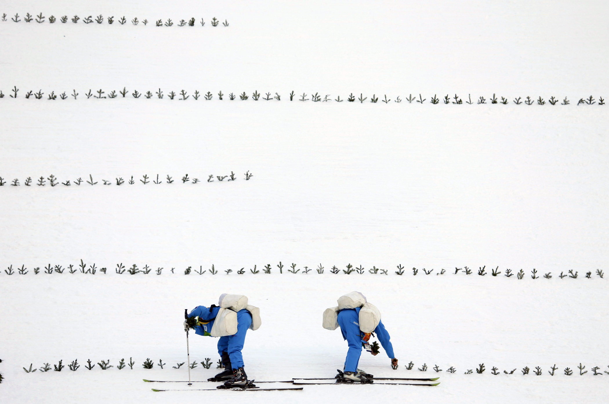 Workers prepare the hill in the ski jumping stadium prior to the 2014 Winter Olympics, Wednesday, Feb. 5, 2014, in Krasnaya Polyana, Russia.