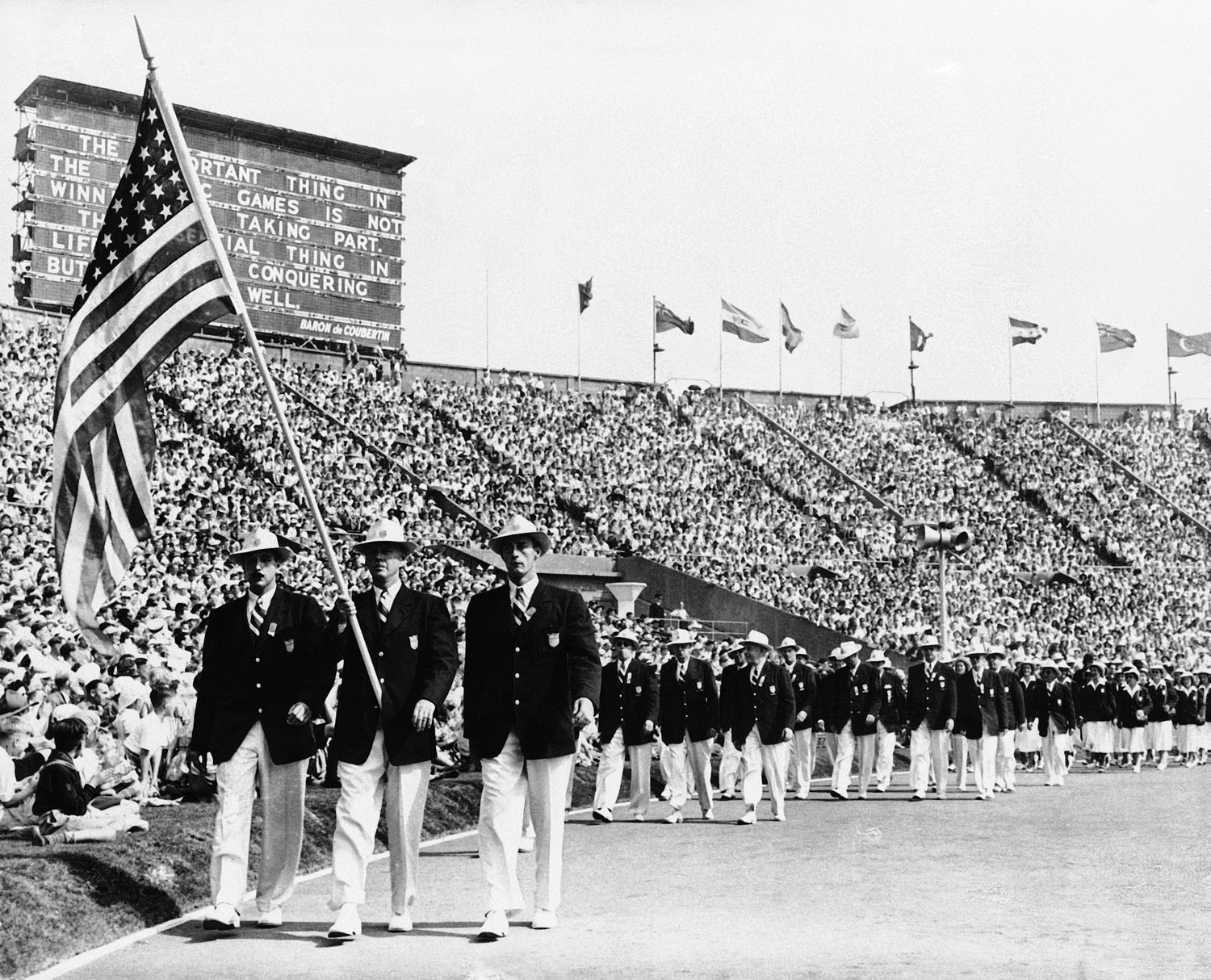Yachter Ralph Craig, center, of Albany, N.Y., carries the American flag in the parade of the nations at the opening of the summer Olympic games in London's Wembley Stadium, July 29, 1948.
