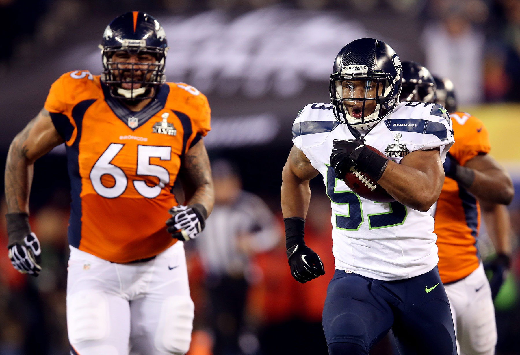 Outside linebacker Malcolm Smith of the Seattle Seahawks runs 69-yards for a touchdown against guard Louis Vasquez of the Denver Broncos after intercepting a pass intended for running back Knowshon Moreno of the Denver Broncos in the second quarter.