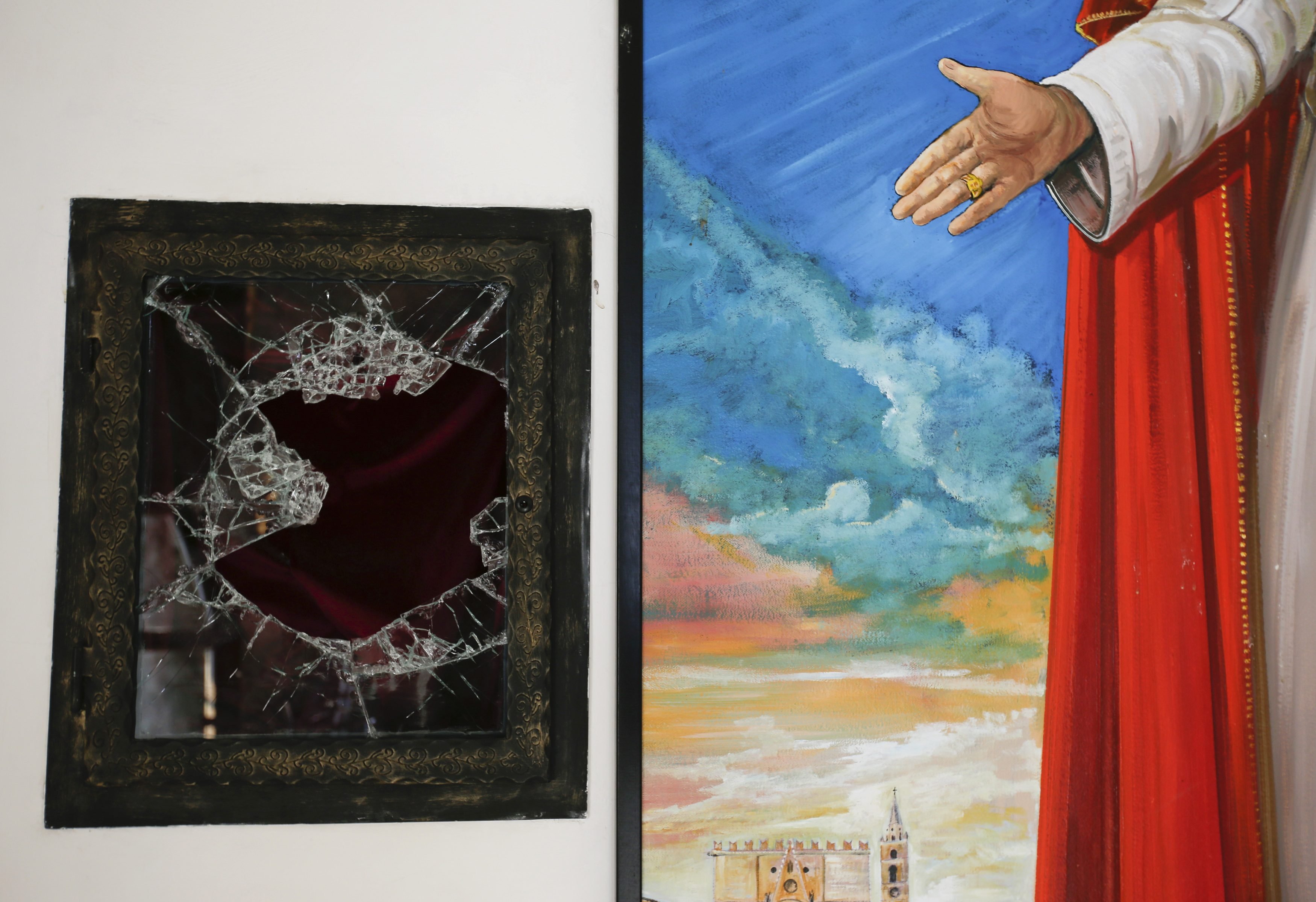 A broken glass of a niche where the reliquary with the blood of the late Pope John Paul II was located is seen next to a painting of the late Pope in the small mountain church of San Pietro della Ienca, near the city of L'Aquila Jan. 28, 2014 .Thieves broke into a small church in the mountains east of Rome and stole the reliquary with the blood of the late Pope John Paul II, a custodian said.