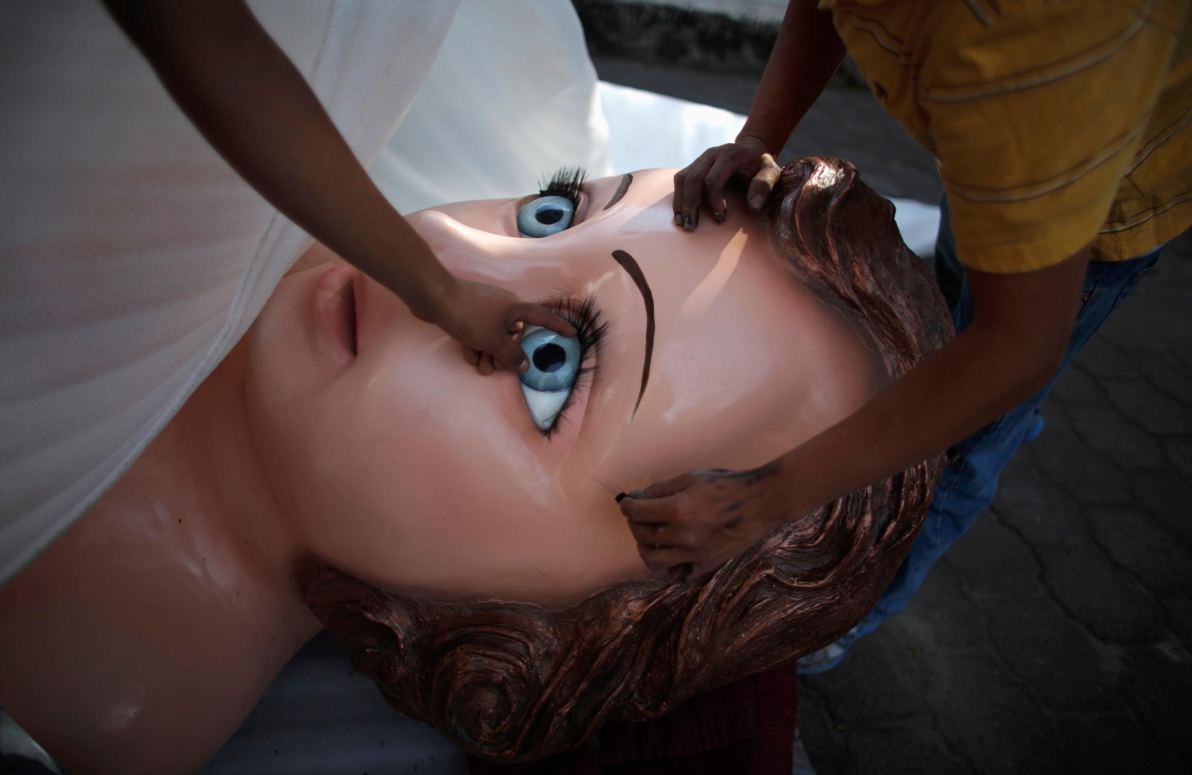 Members of the Morphix Group inspect the eyelashes of a baby Jesus statue to be displayed during the annual Candlemas celebrations at the Sanctuary of the Lord of the Holy Sepulchre in the Iztapalapa borough of Mexico City February 1, 2014.