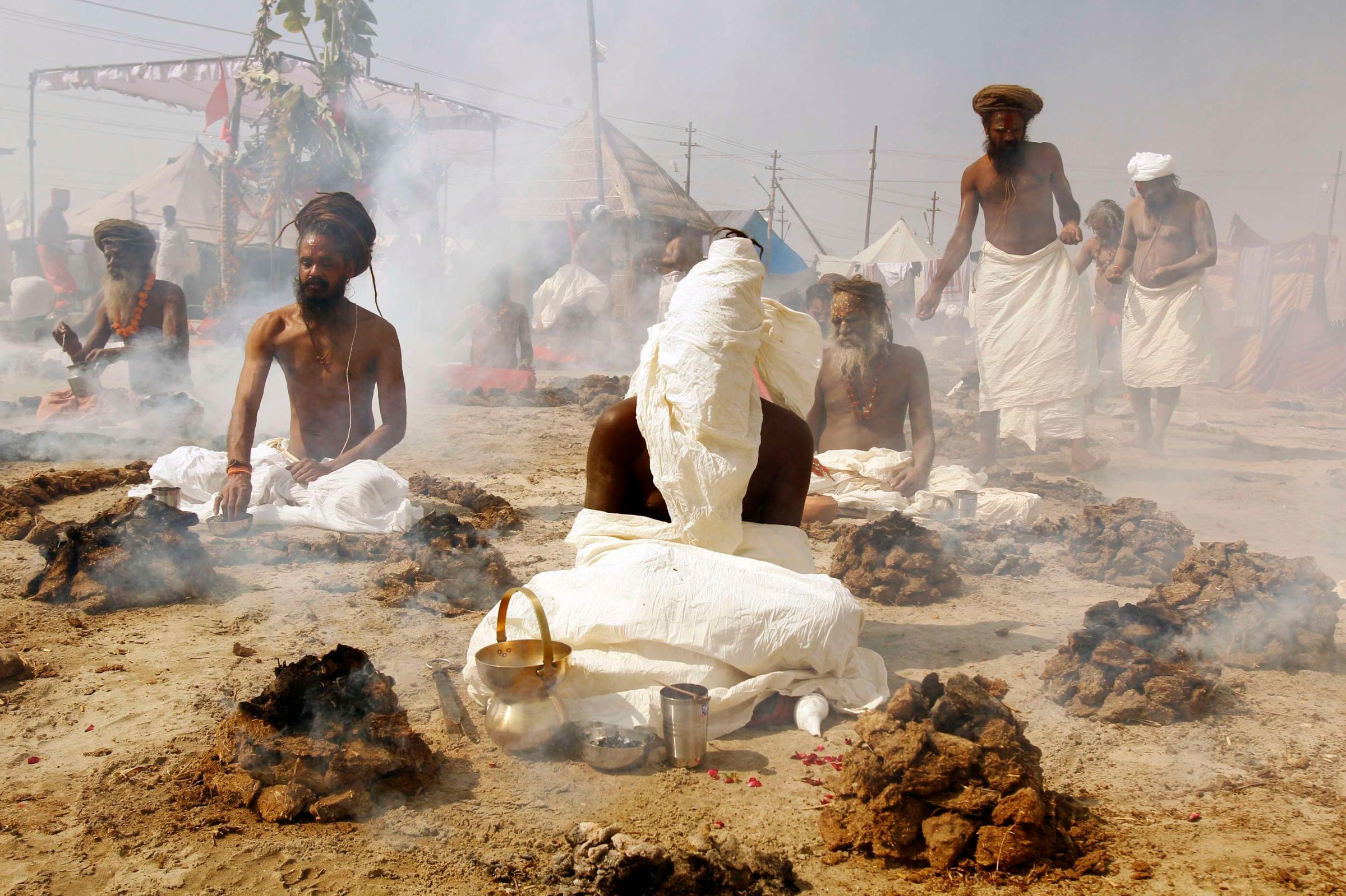 Sadhus, or Hindu holy men, perform prayers while sitting inside circles of burning "Upale" (or dried cow dung cakes) on the banks of the river Ganges during the Magh Mela festival in the northern Indian city of Allahabad Feb. 4, 2014.