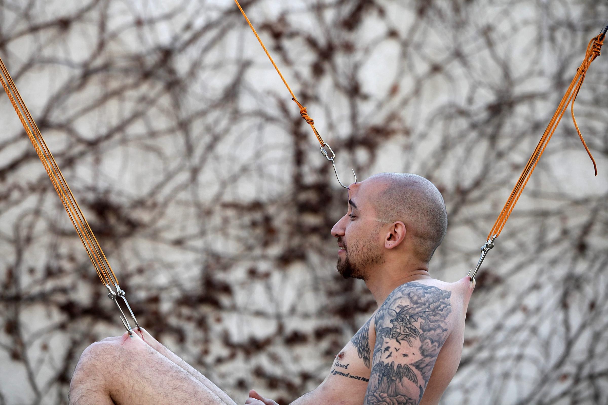 An Israeli hanging on hooks performs the Suspension (body modification) during the annual Israel Tattoo Convention in Tel Aviv, Israel, Feb. 8, 2014. The event took place for the second time in Israel featuring the best tattoo artists of the country.