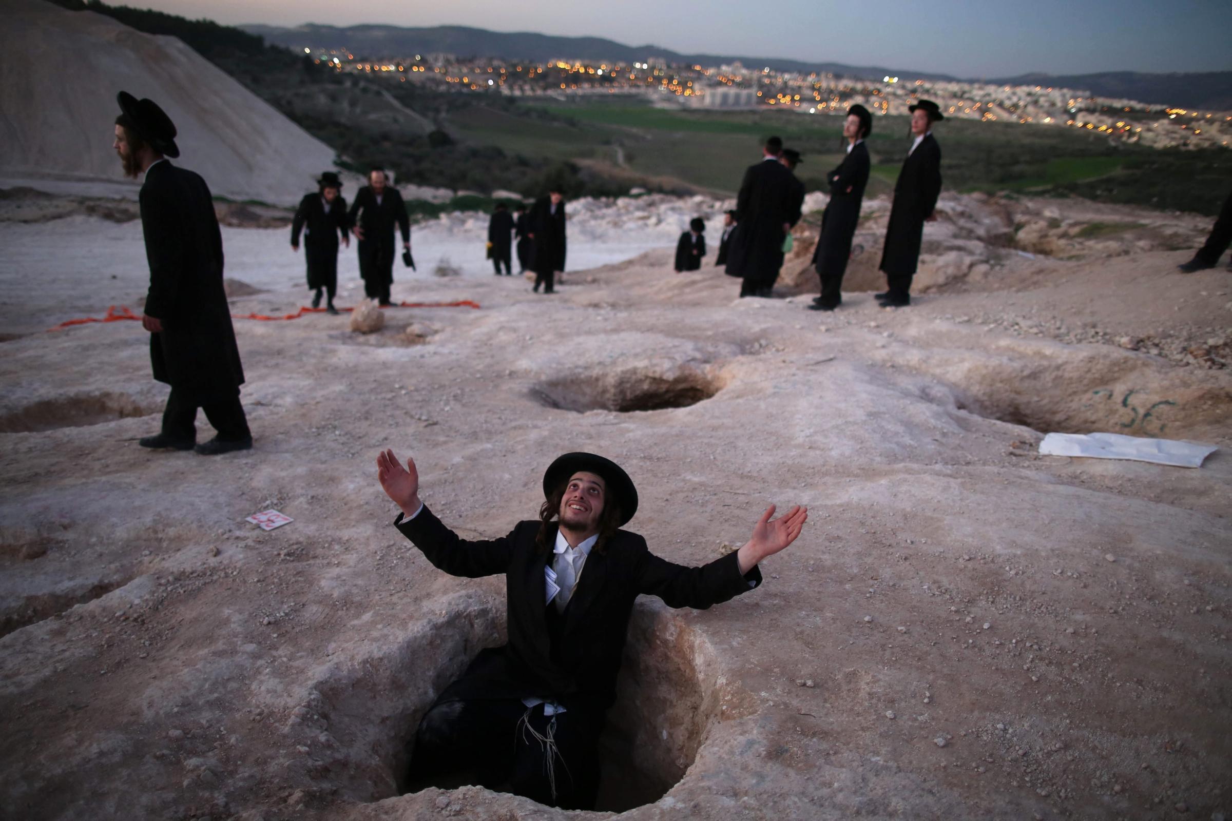 An Ultra-Orthodox Jewish man sits in a hole and prays during a demonstration in Beit Shemesh, Israel, Feb. 12, 2014. Hundreds of Ultra-Orthodox Jews protested against the construction of new housing units, believing they would be built at the site of ancient Jewish graves.