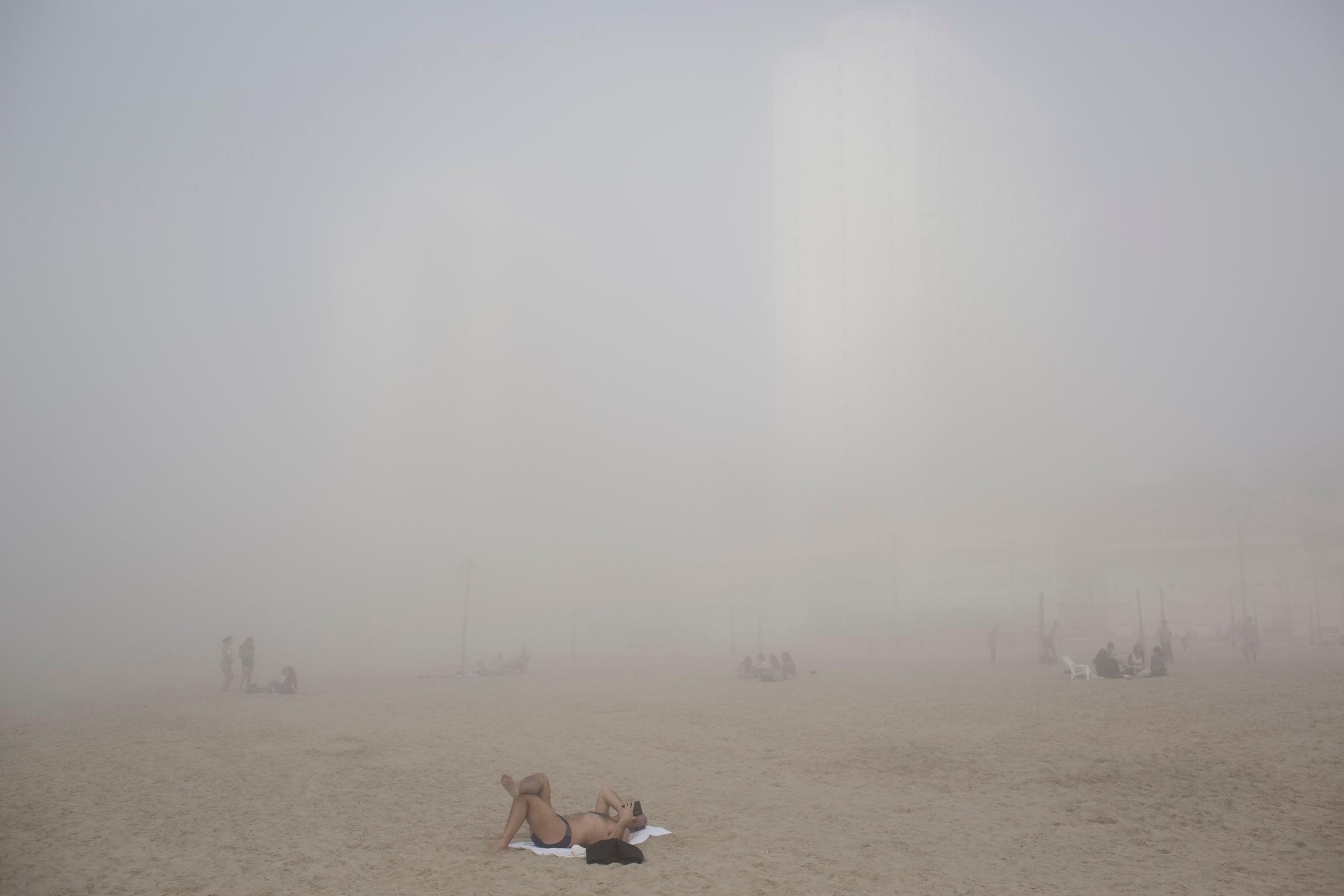 Israelis enjoy the beach under heavy fog at the Mediterranean Sea beach front in Tel Aviv, Feb. 20, 2014.