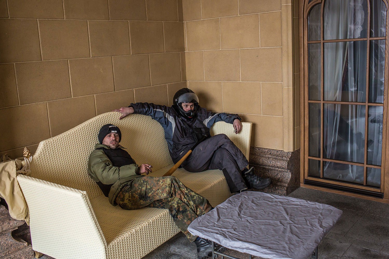 Anti-government protesters sit on a couch on a back patio.