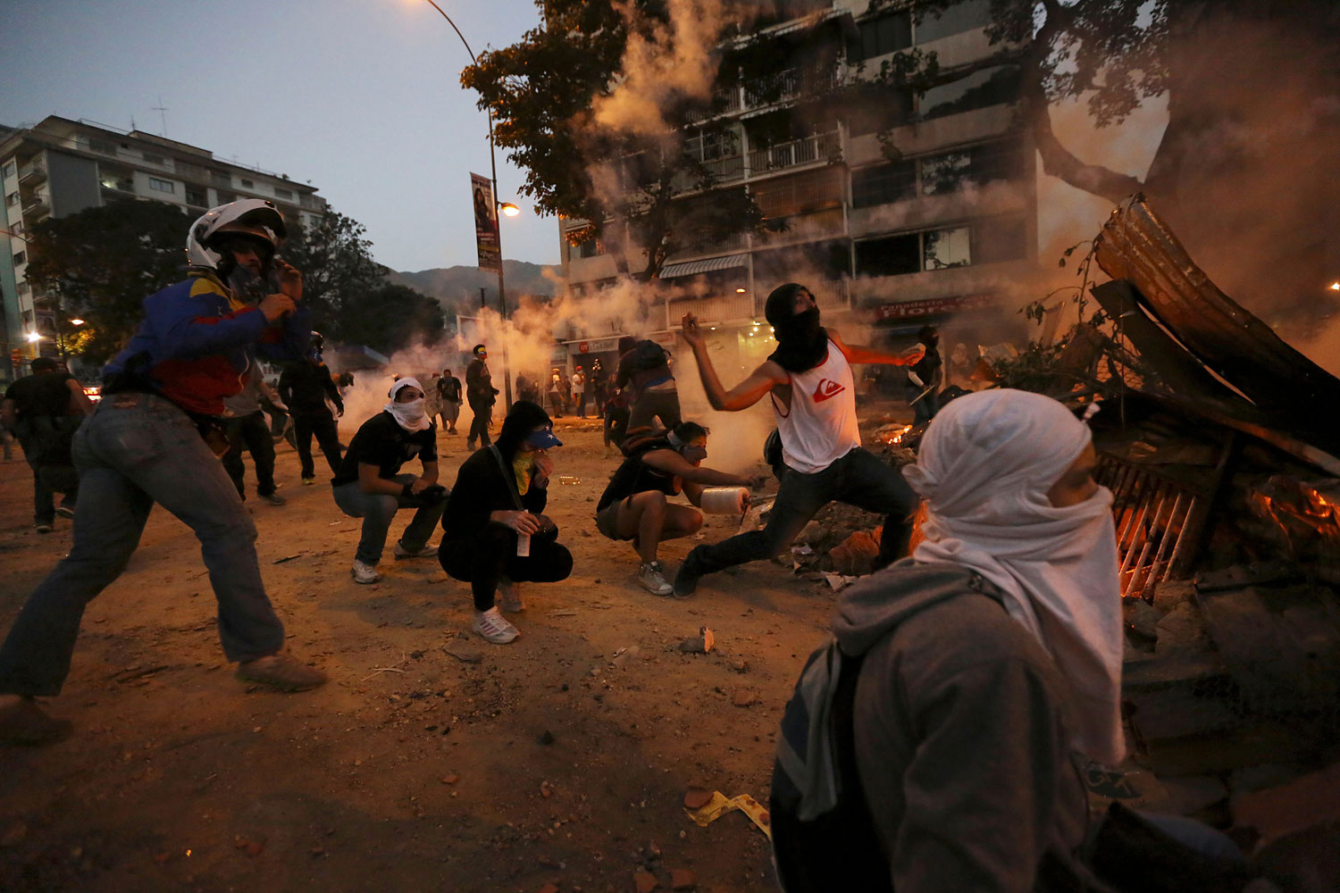 Masked demonstrators throw stones at Bolivarian National Police during clashes in Caracas, March 3, 2014.