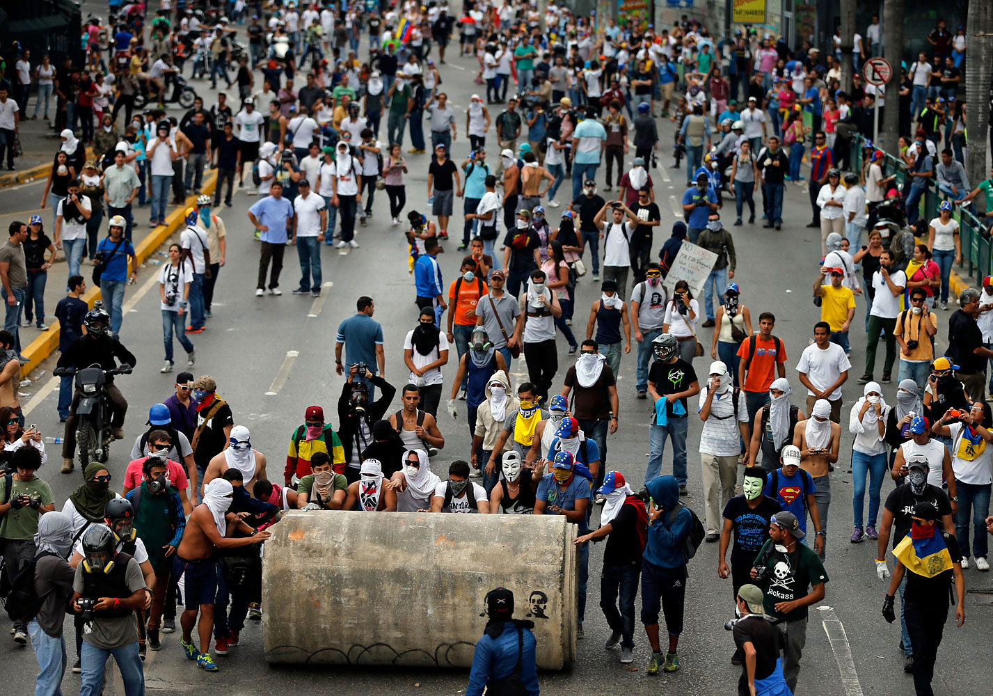 Demonstrators roll a water pipe in an attempt to block a major highway during clashes with the Bolivarian National Guard in Caracas, Feb. 27, 2014.