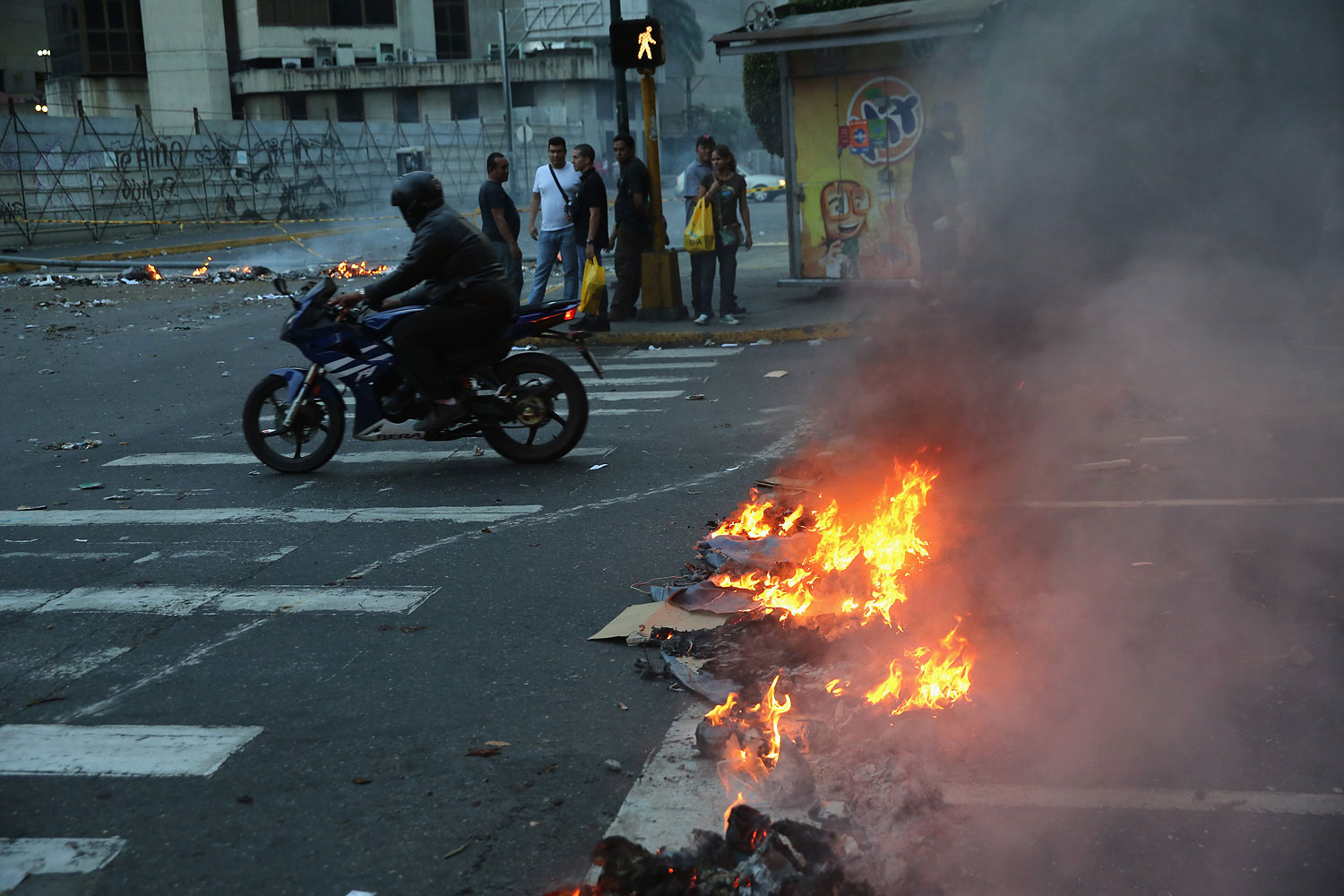 A motorcyclist rides through burning debris after an anti-government demonstration on Feb. 27, 2014 in Caracas.