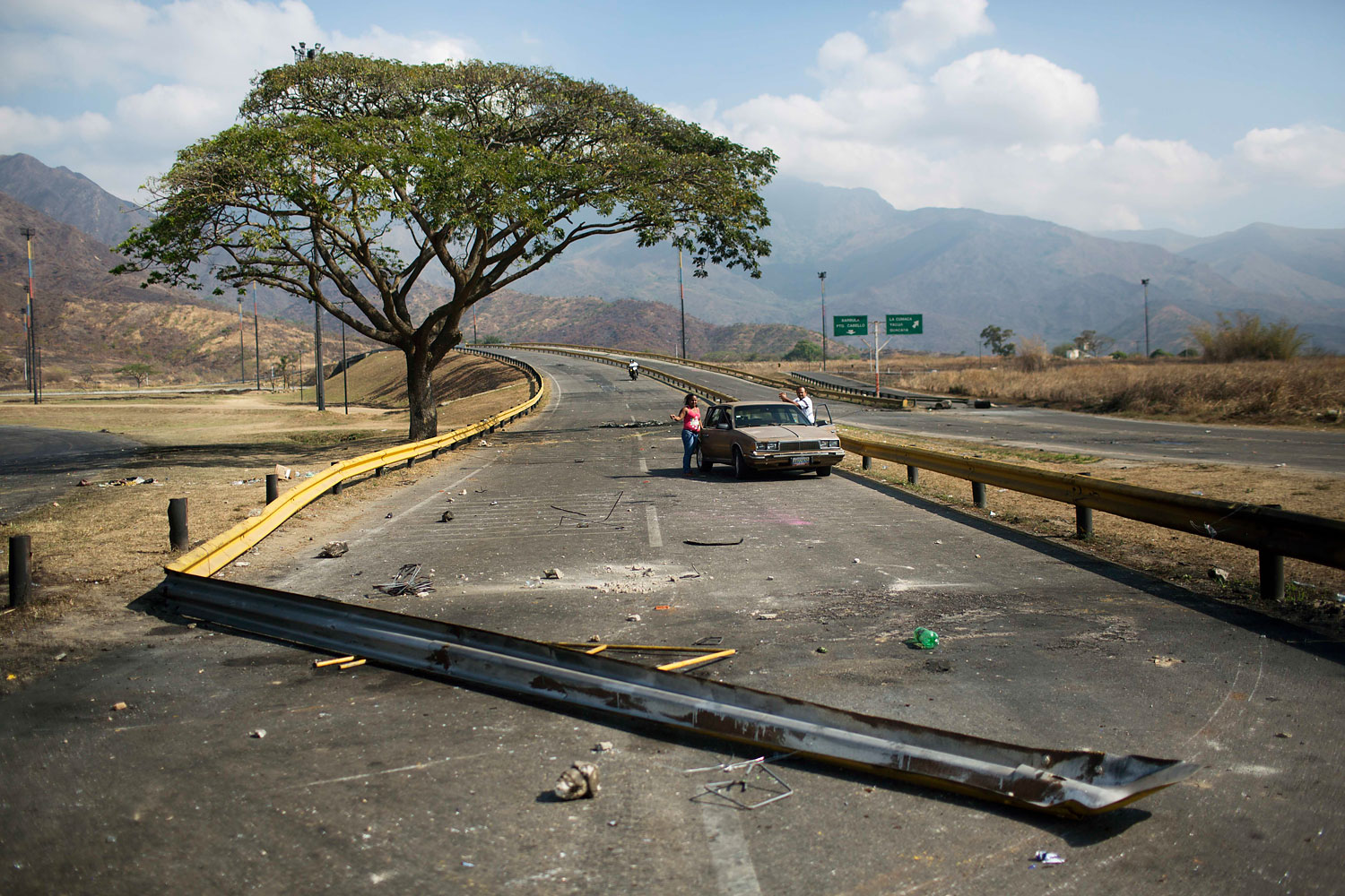 A couple stand next to their car trapped between barricades set up by anti-government protesters, in Valencia, Venezuela, Feb. 27, 2014.