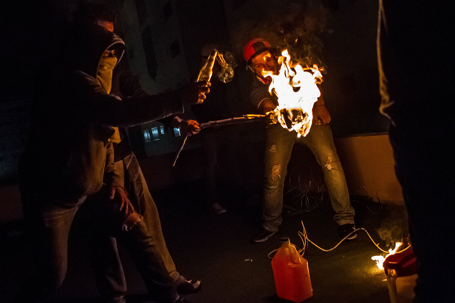 Protesters on a rooftop light Molotov cocktails to throw at police below in San Cristobal, Venezuela, in the pre-dawn hours of Feb. 24, 2014.