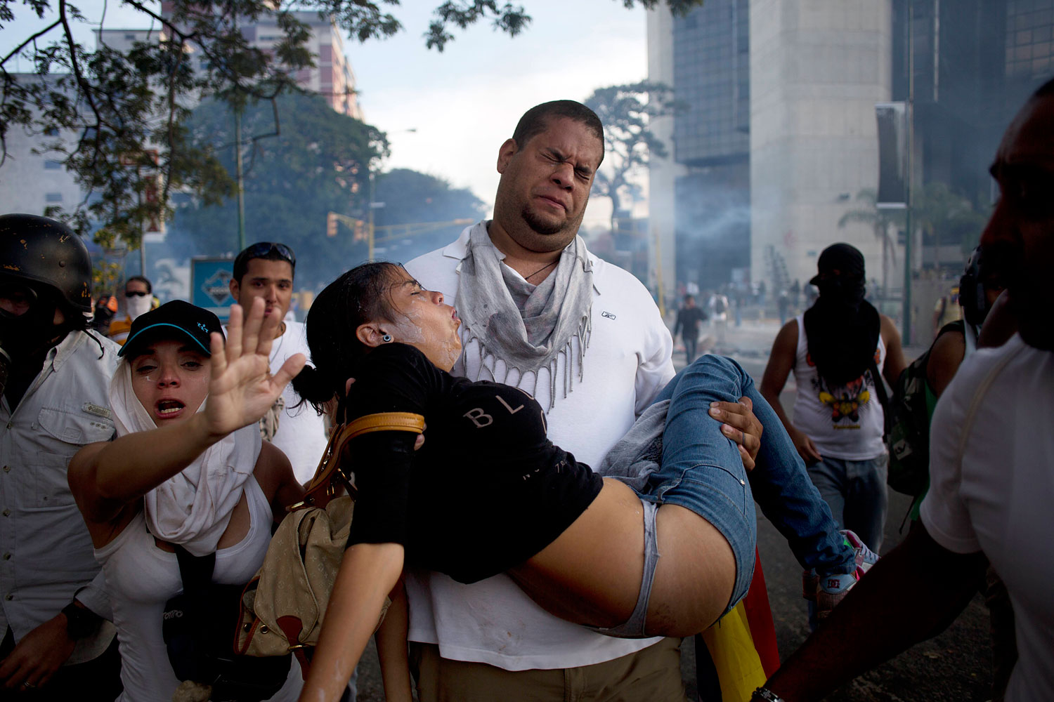 A man carries a woman affected by tear gas launched by riot police at anti-government protesters in Caracas, Feb. 22, 2014.
