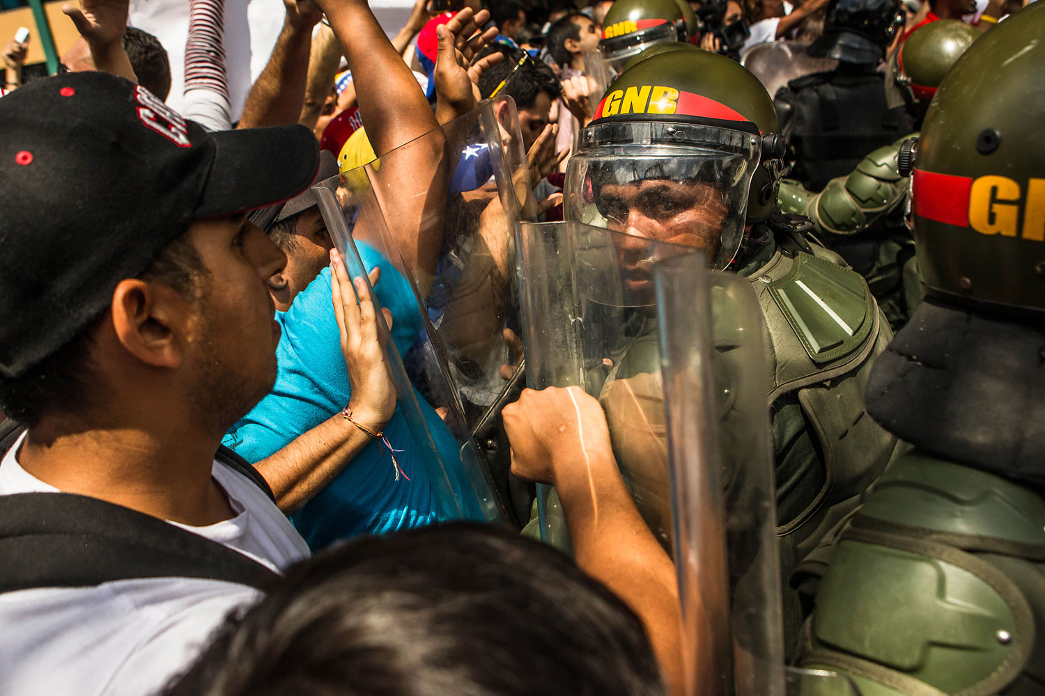 Lopez supporters clash with riot police in effort to block the path of the armored vehicle carrying Leopoldo Lopez after he surrendered to the police, in Caracas, Feb. 18, 2014.