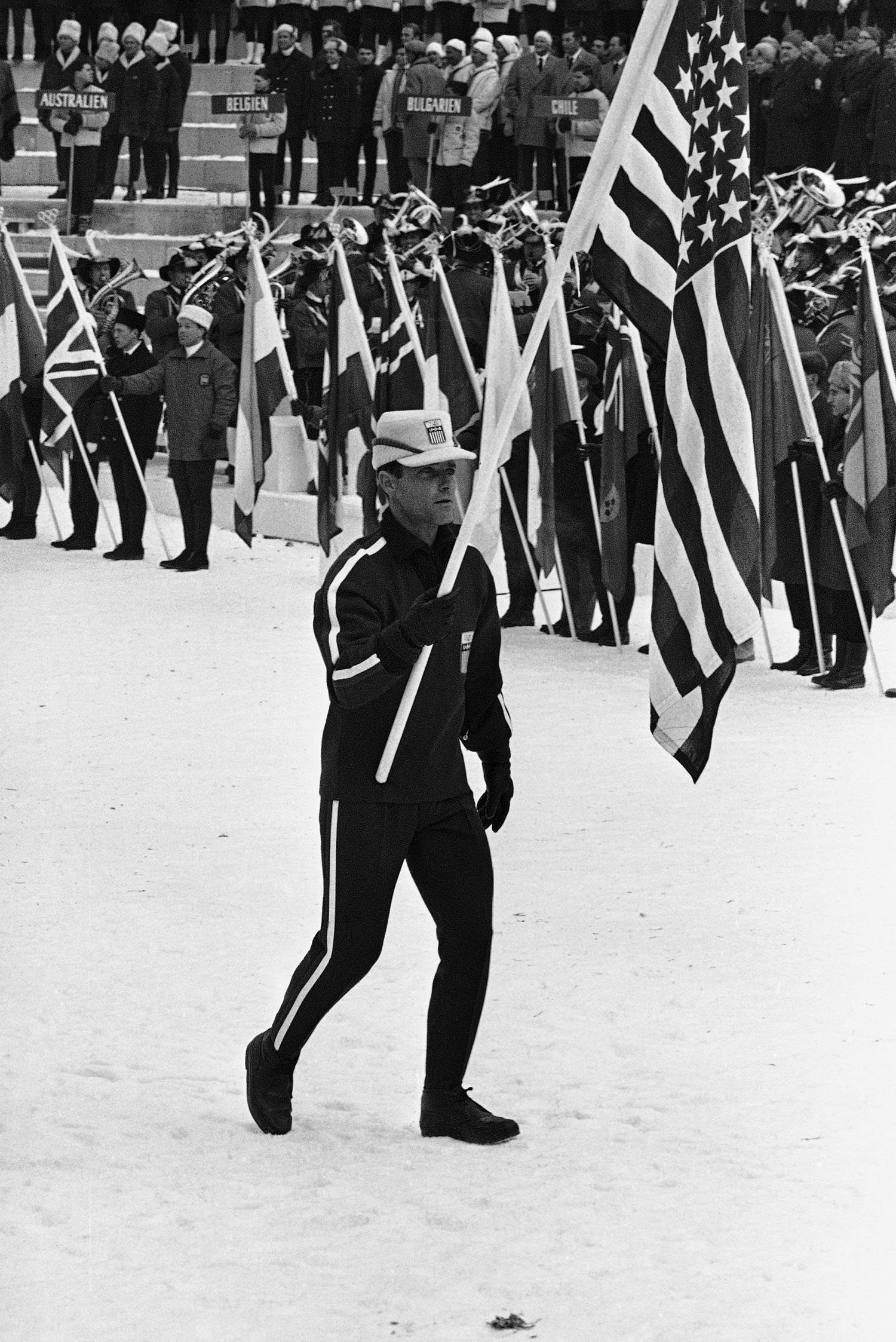Speedskater Bill Disney carries the flag as he leads his team into the Olympic Ski Stadium at Bergisel for the opening ceremony of the 1964 Winter Olympics in Innsbruck, Austria.