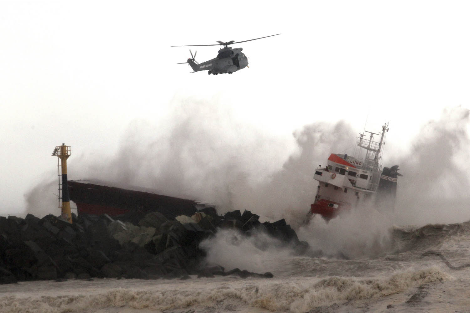 Feb. 5, 2014. A military helicopter flies over a Spanish cargo ship that slammed into a jetty in choppy Atlantic Ocean waters off Anglet, southwestern France.