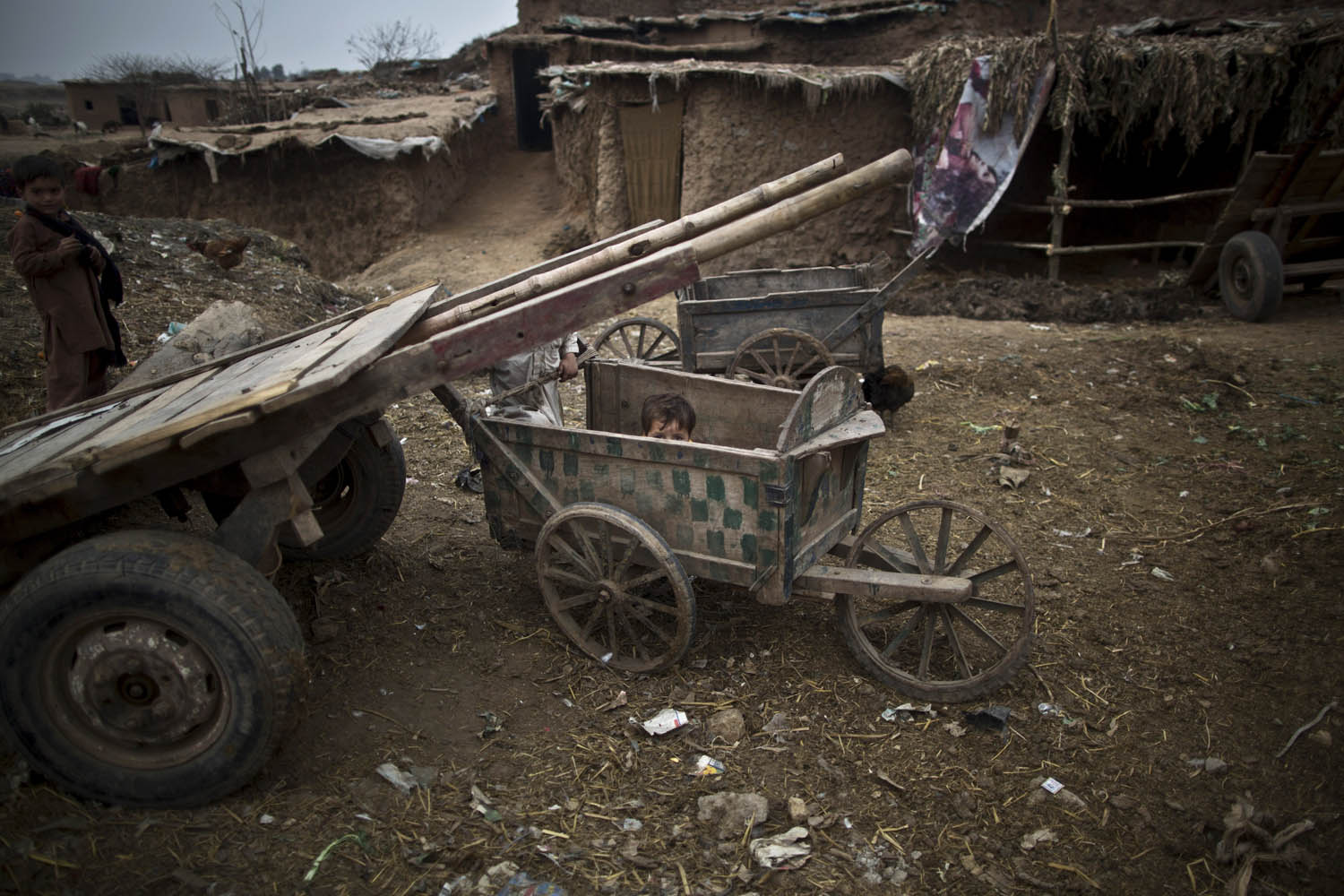 Feb. 2, 2014. An Afghan refugee child hides in a wooden-cart placed near his home in a poor neighborhood on the outskirts of Islamabad.