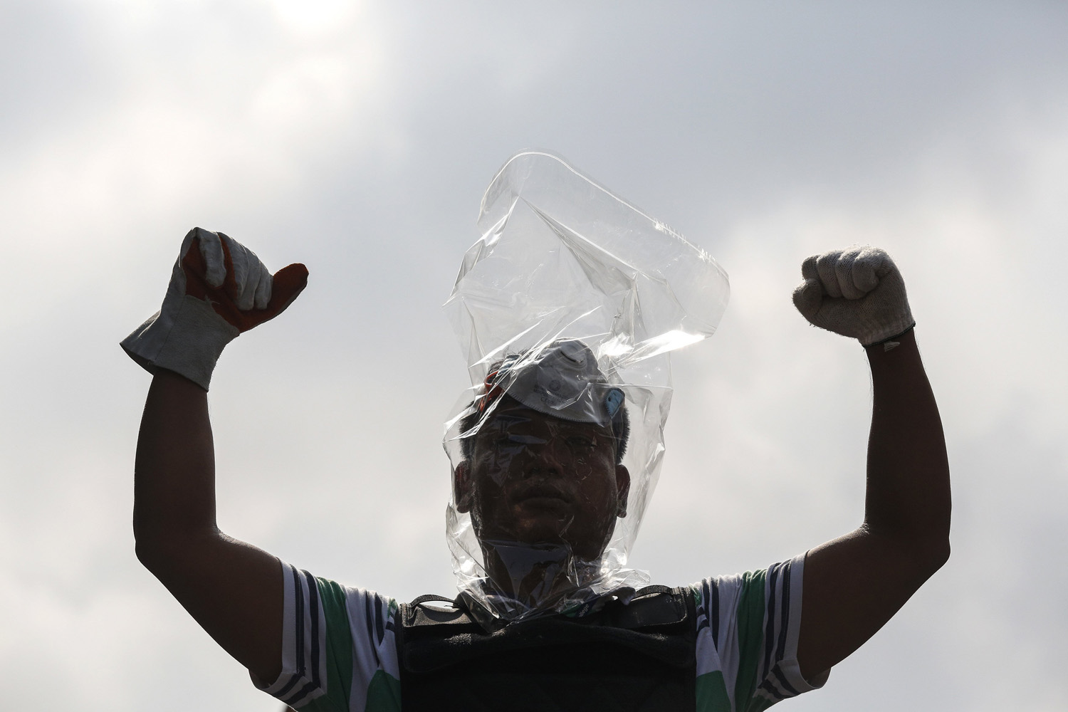 An anti-government protester with his head covered with a plastic bag, gestures near the Government House in Bangkok