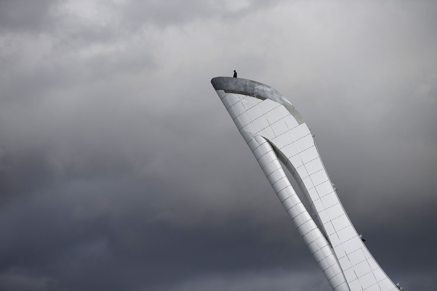 Feb. 4, 2014. A worker is dwarfed against the sky as he stands at the top of the Olympic cauldron ahead of the 2014 Winter Olympics in Sochi, Russia.