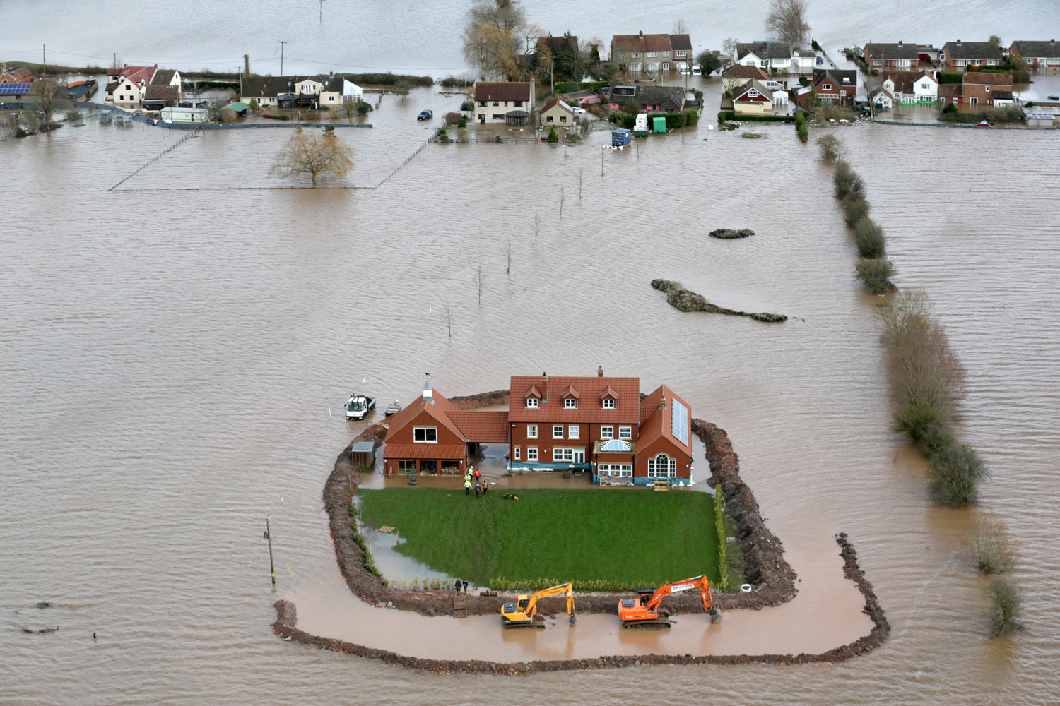 Feb. 10, 2014. Worker's continue to build flood defense around Moorland resident Sam Notaro's house in the flooded village of Moorland near Bridgwater on the Somerset Levels in Somerset, England.