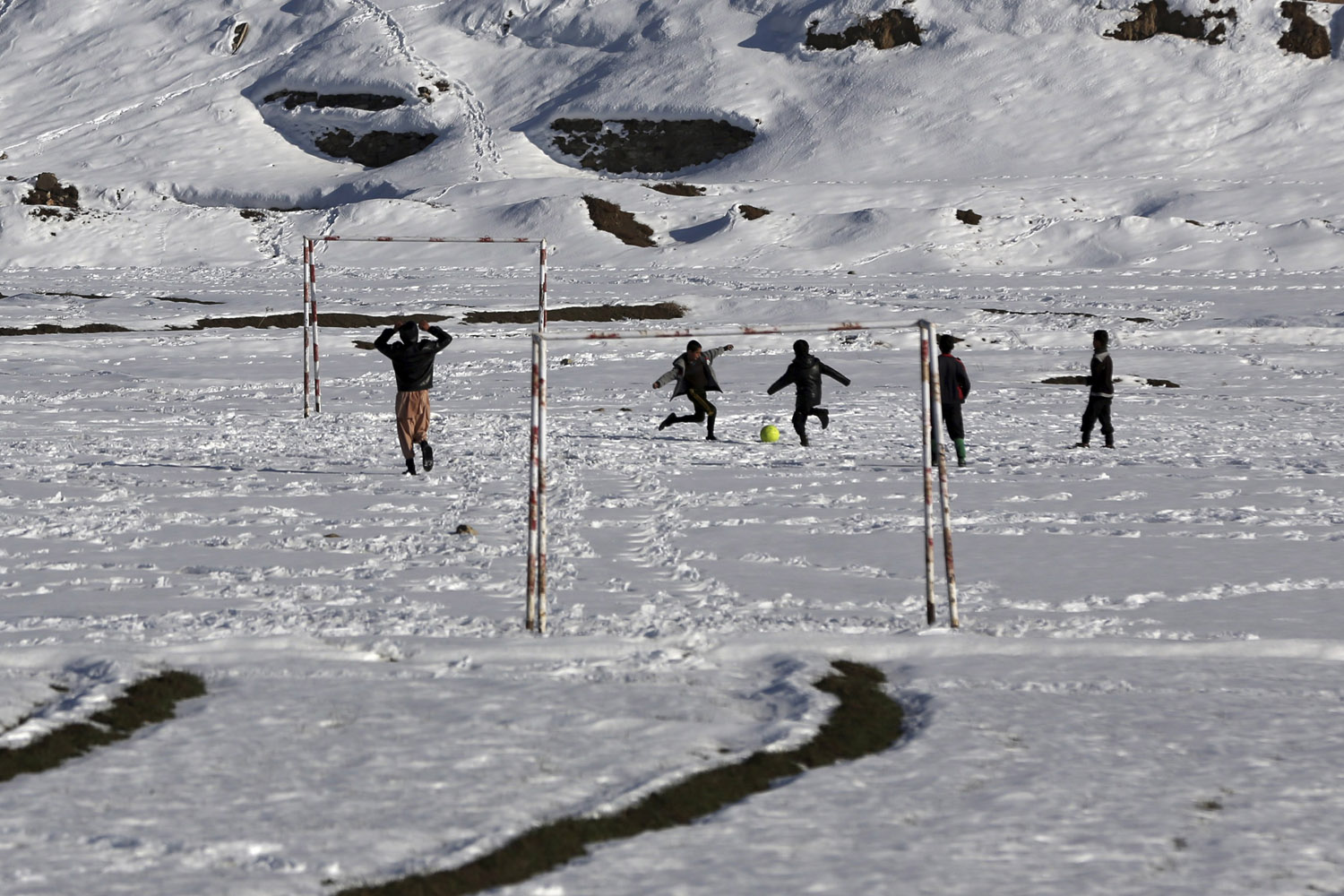 Feb. 11, 2014. Afghan boys play soccer in a desolate snow-covered village on the outskirts of Kabul.