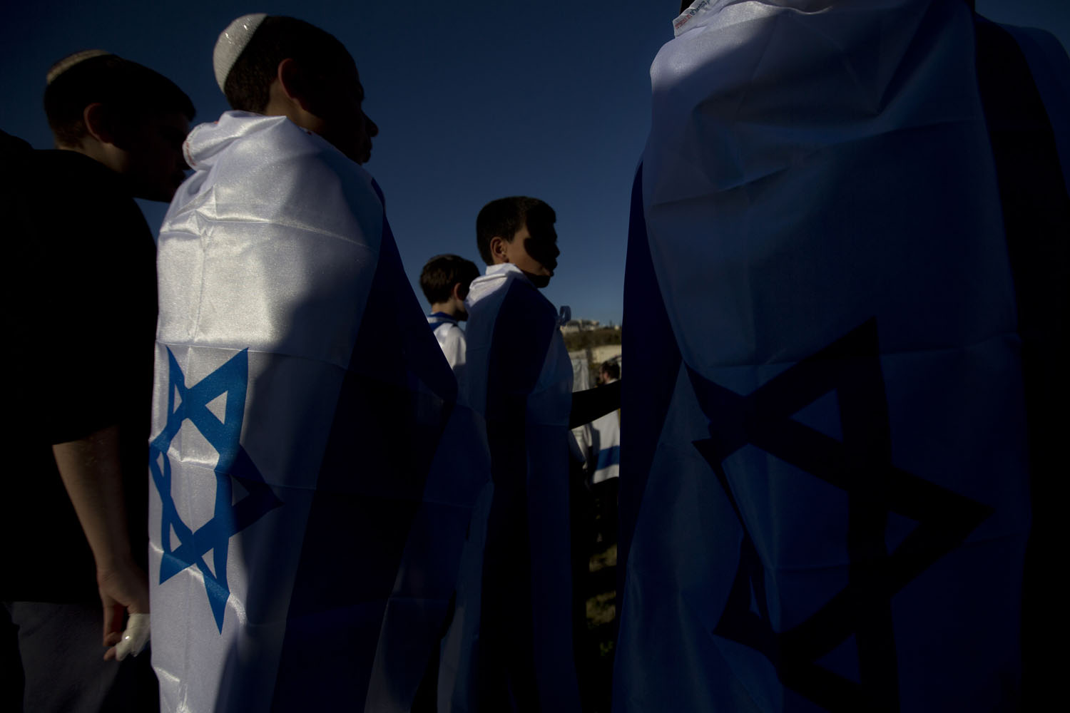 Feb. 13, 2014. Israeli youths stand covered with national flags prior to a march from the West Bank settlement of Maaleh Adumim, to the E-1 area on the eastern outskirts of Jerusalem.