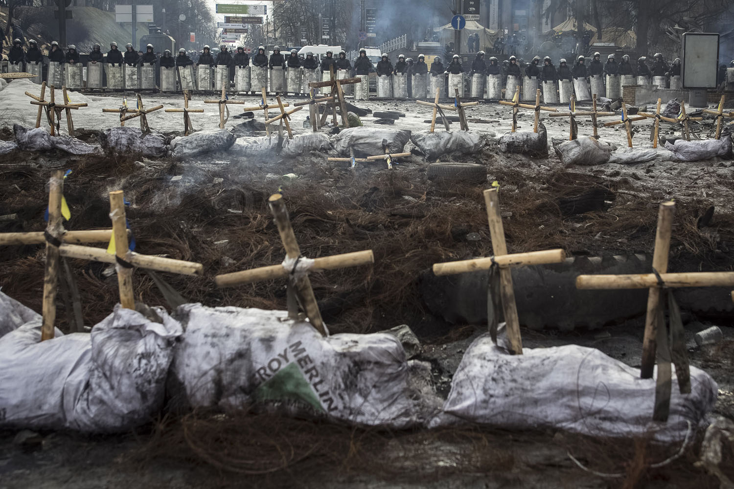 Feb. 11, 2014. Riot police stand behind crosses installed by anti-government protesters in memory of the people who have died and went missing during clashes in Ukraine, near the barricades in Kiev.