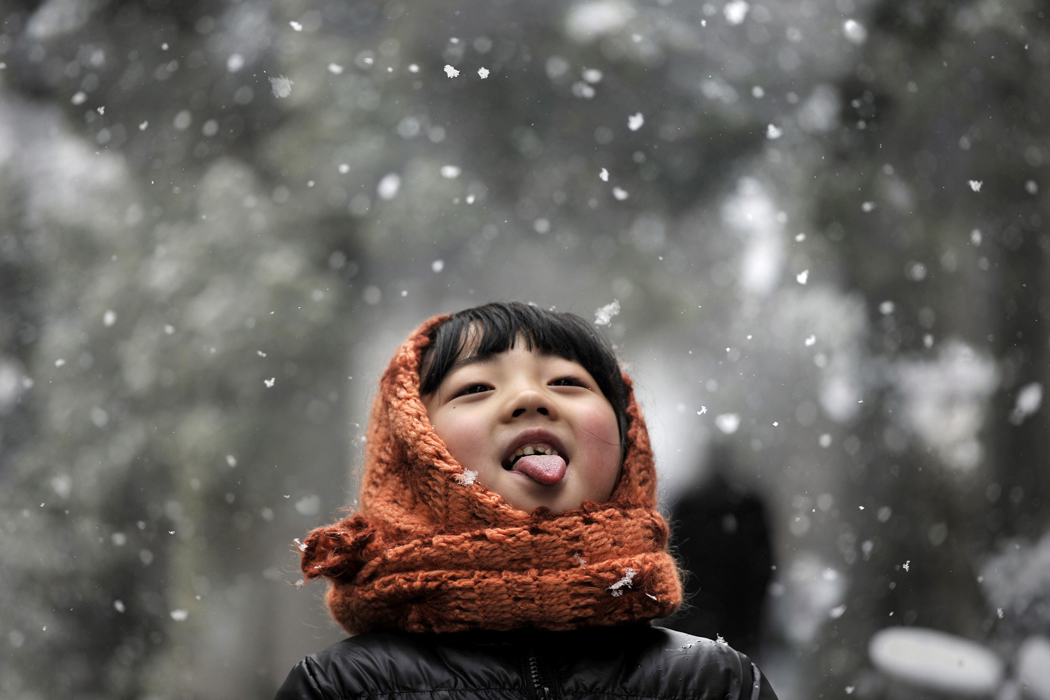 A girl sticks out her tongue during snowfalls on a street in Hefei