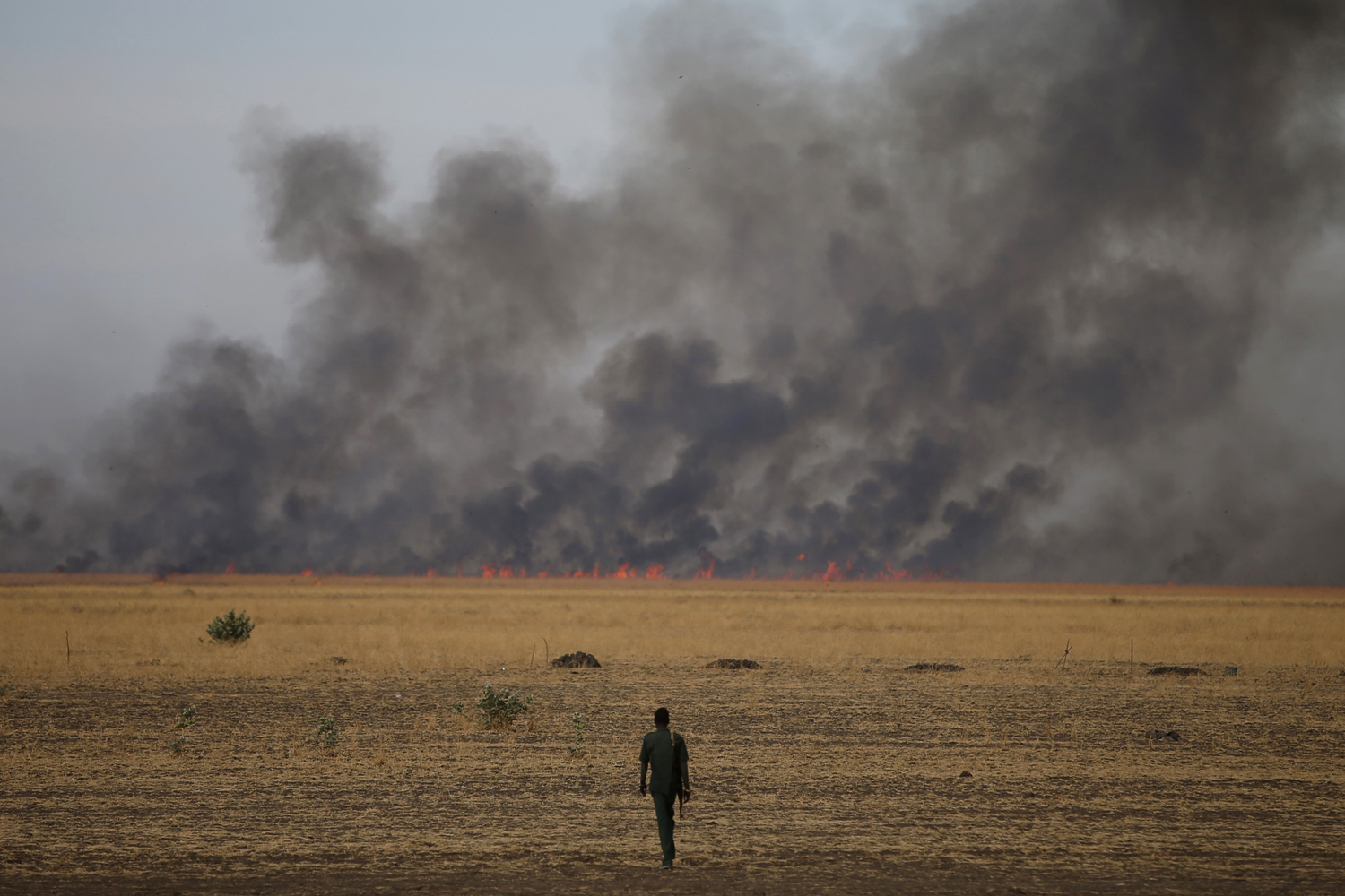 Feb. 13, 2014. A rebel fighter walks in front of a bushfire in a rebel controlled territory in Upper Nile State, South Sudan.