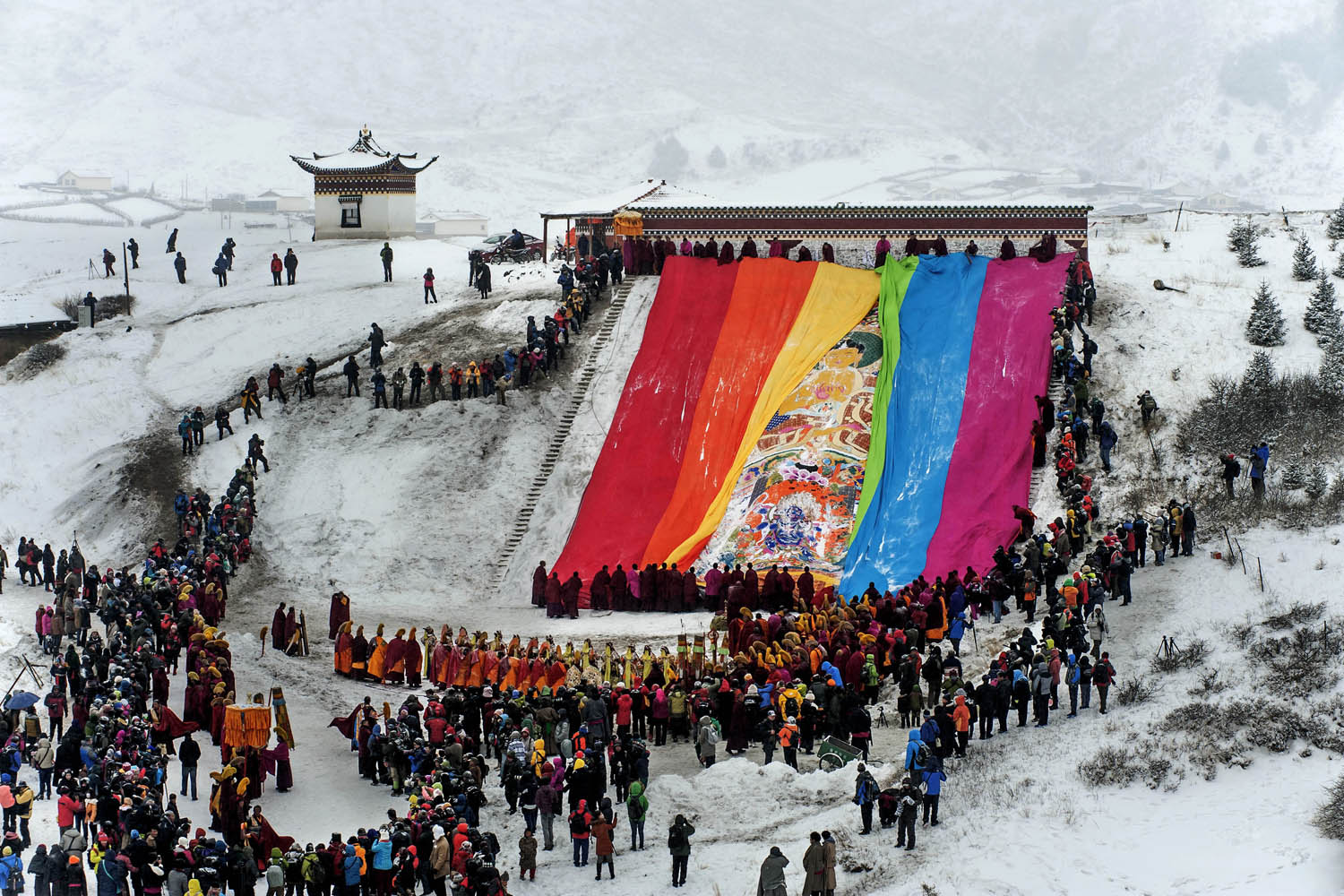 Feb. 12, 2014. Visitors and Tibetan monks look on as a giant thangka, a religious silk embroidery or painting displaying the Buddha portrait, is unveiled amid snowfalls at Langmu Lamasery in Gannan Tibetan Autonomous Prefecture, Gansu province.