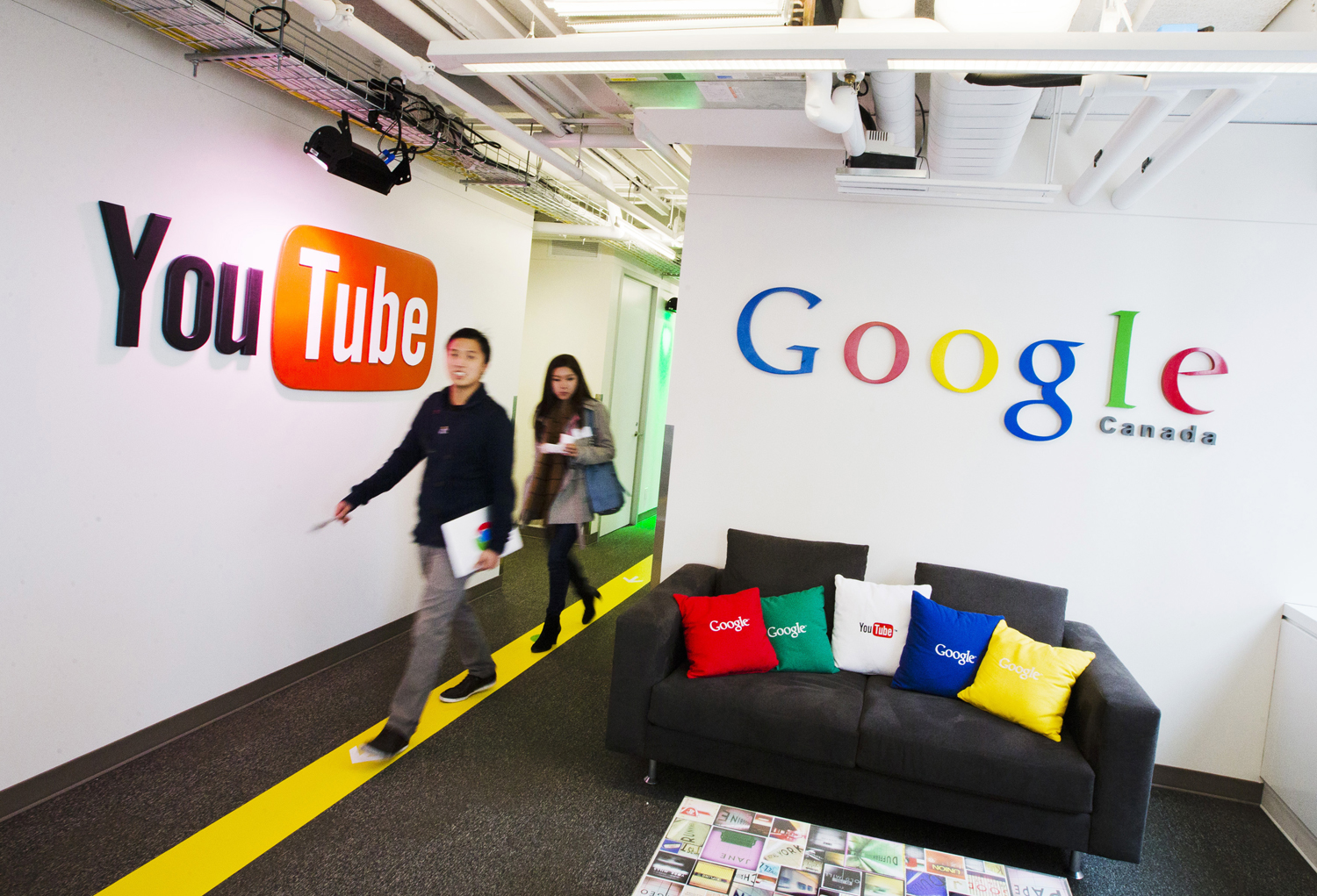 People walk by a YouTube sign at the new Google office in Toronto, Nov. 13, 2012.  