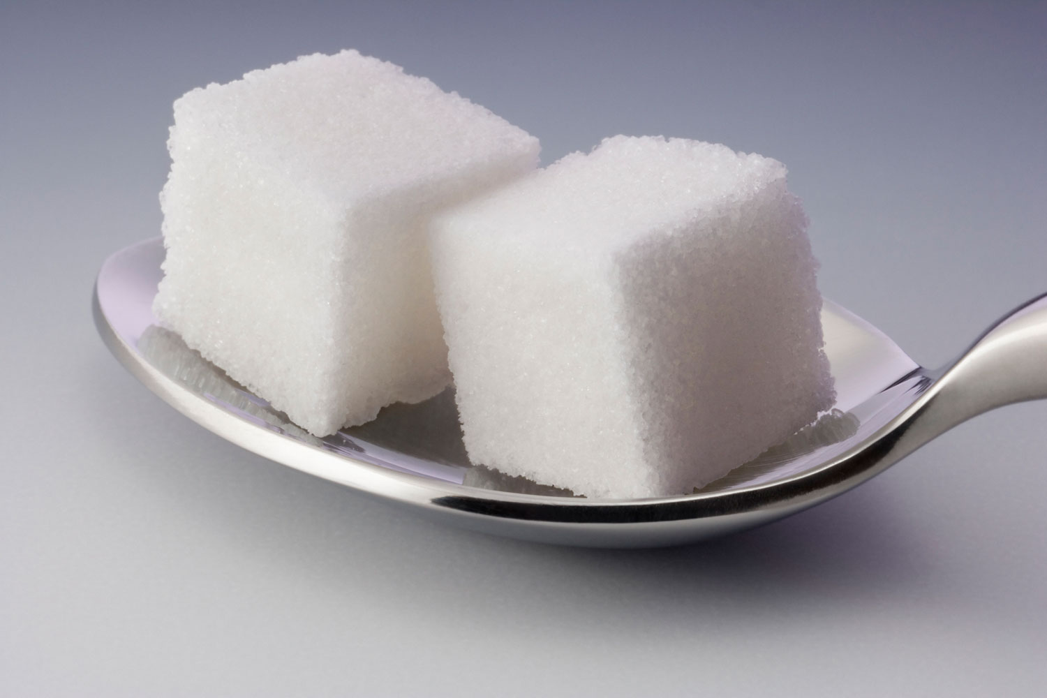 Two sugar cubes on spoon, close-up (still life)