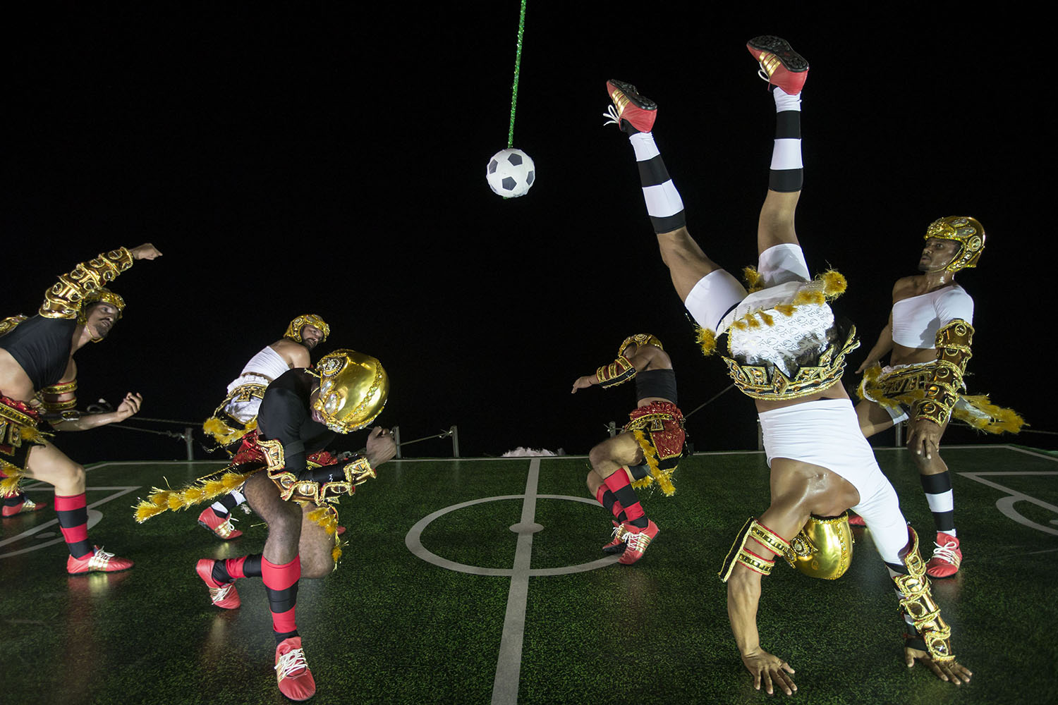 Mar. 4, 2014. Performers from the Imperatriz Leopoldinense samba school pretend to play soccer as they hang on the wall of a float during carnival celebrations at the Sambadrome in Rio de Janeiro.