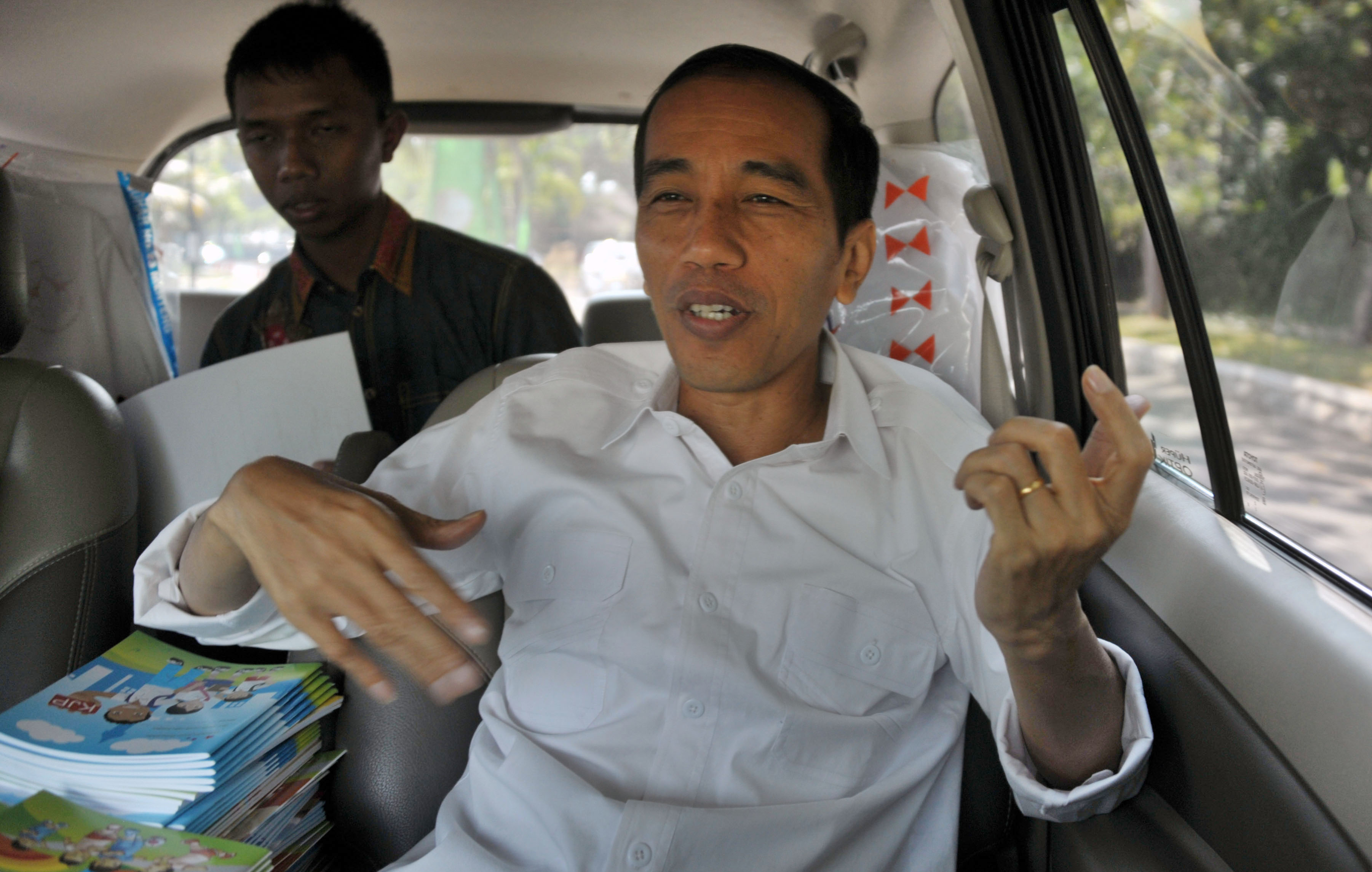 This picture taken on August 22, 2013, Jakarta governor Joko Widodo, a rock fan makes an air guitar gesture as he travels on a van on the way to make sight inspection in Jakarta city. (BAY ISMOYO—AFP/Getty Images)