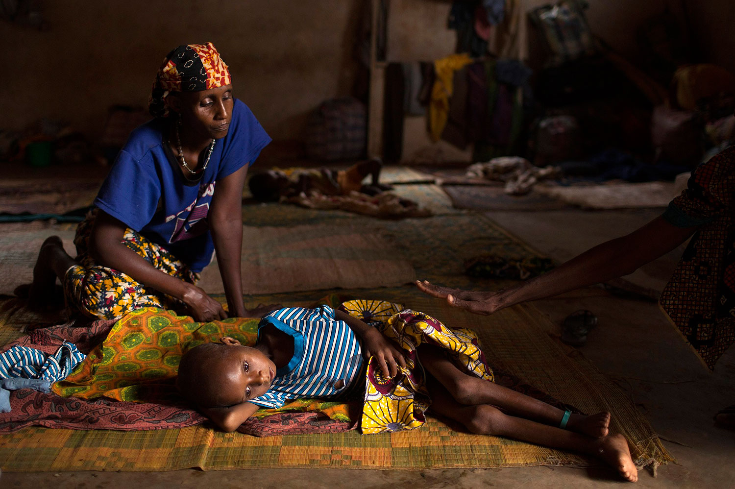 Relatives sit near Aliou Abalaye, 4, as he lies sick on the floor near Kilometre 12 (PK12), in Bangui, Central African Republic, where internally displaced Muslims are stranded due to the ongoing sectarian violence, on March 6, 2014. (SIEGFRIED MODOLA—REUTERS)