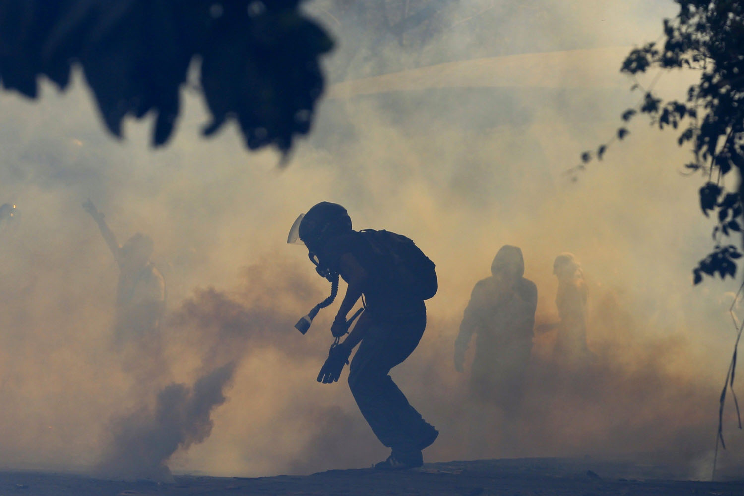 An anti-government protester runs amidst tear gas launched by the police during a protest in Caracas