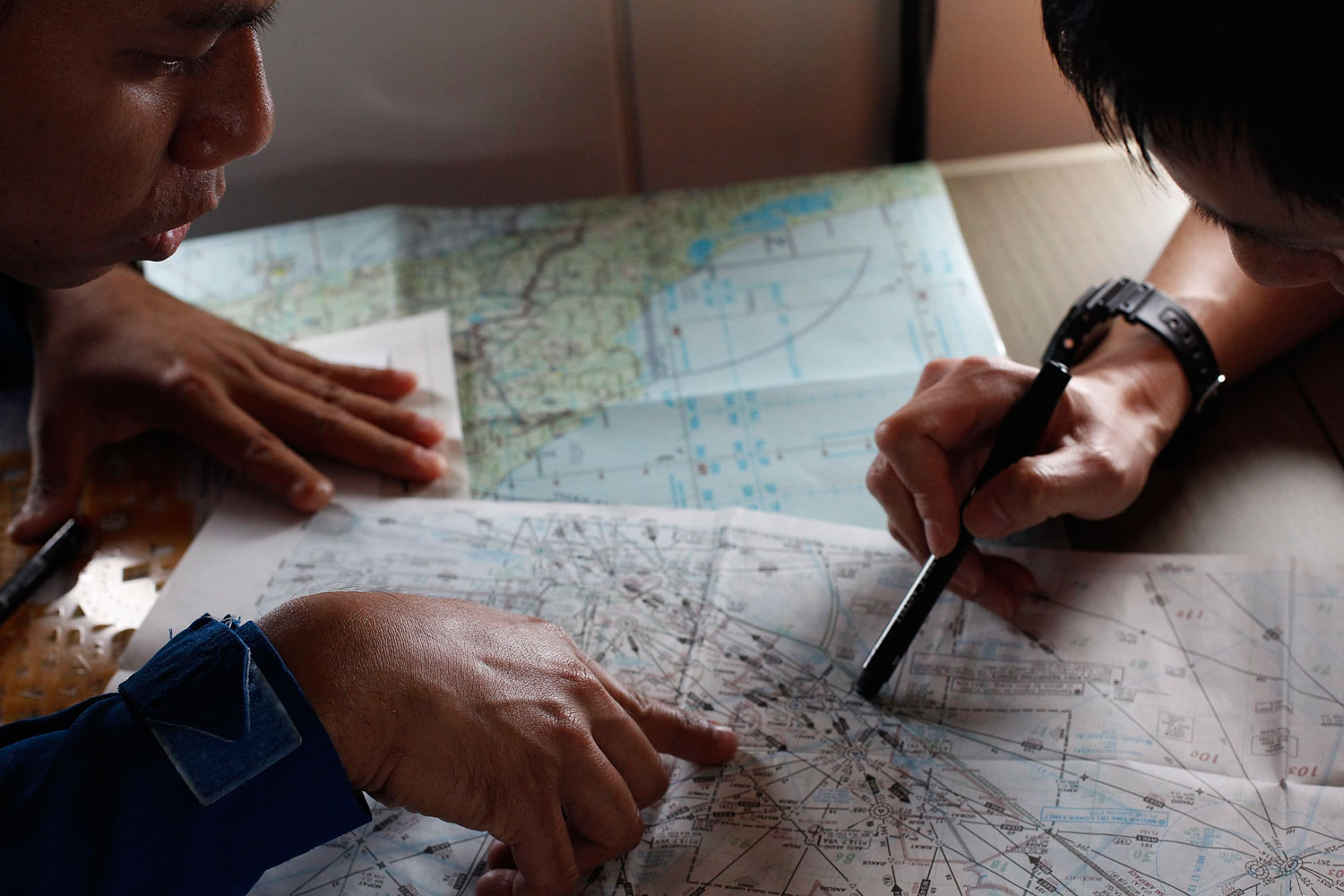 JCG studies a map with a Malaysian Maritime Enforcement Agency pilot in JCG's Gulfstream V Jet aircraft as they search for the missing plane over the South China Sea