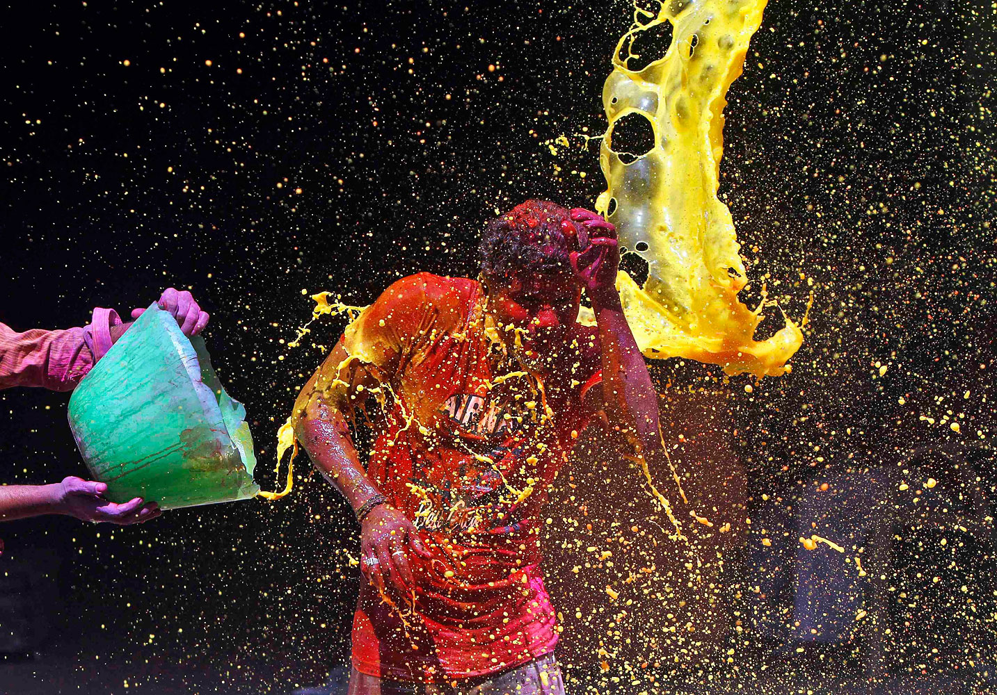 A man reacts to coloured water being splashed over him during Holi celebrations in the southern Indian city of Chennai, March 17, 2014.