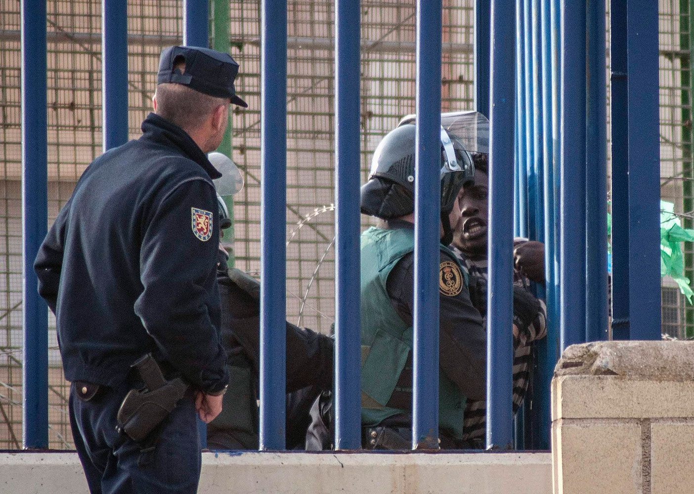 An African migrant is detained by a Spanish civil guard at the border fence near Beni Enza between Morocco and Spain's north African enclave Melilla while attempting to cross into Spanish territory, March 28, 2014.