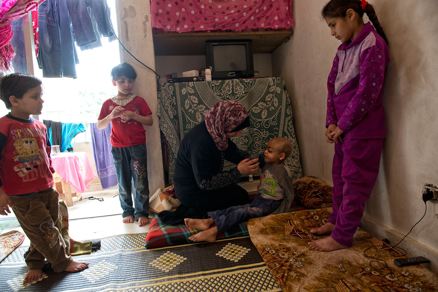Feryal Delly, a Syrian refugee, gives water to her 4-year-old son Zacharia on March 9. Zacharia, who suffers from a brain tumor, lives with his family in a rented apartment in Halt, north of Beirut. 