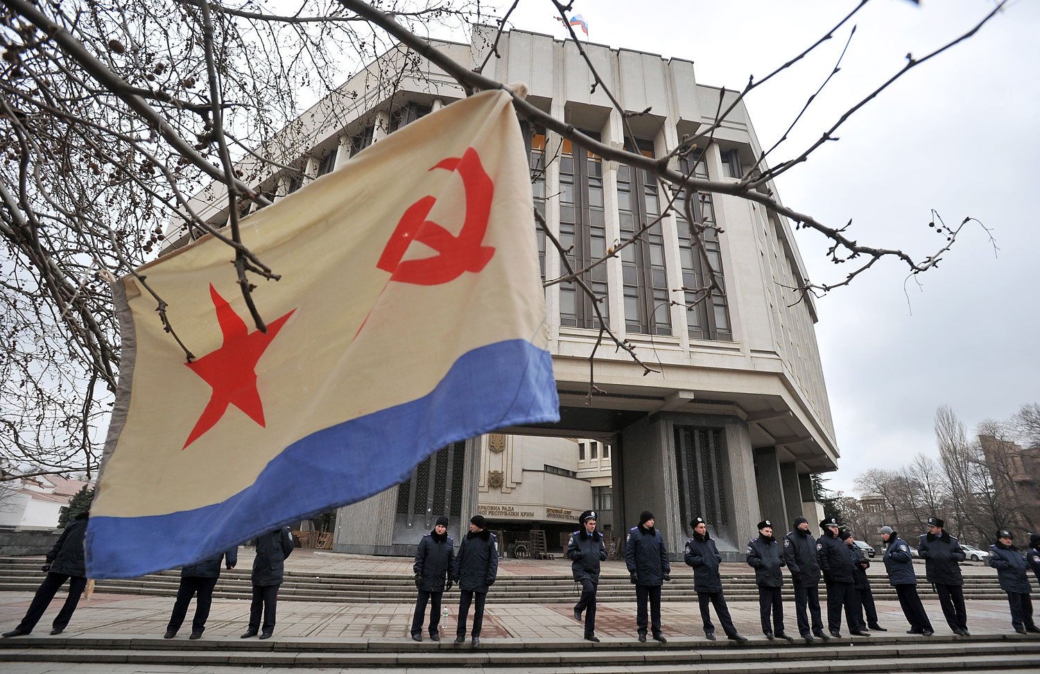 A flag of the Russian Navy hangs from a tree as policemen stand guard in front of the local parliament building on Feb. 28, 2014 in Simferopol.