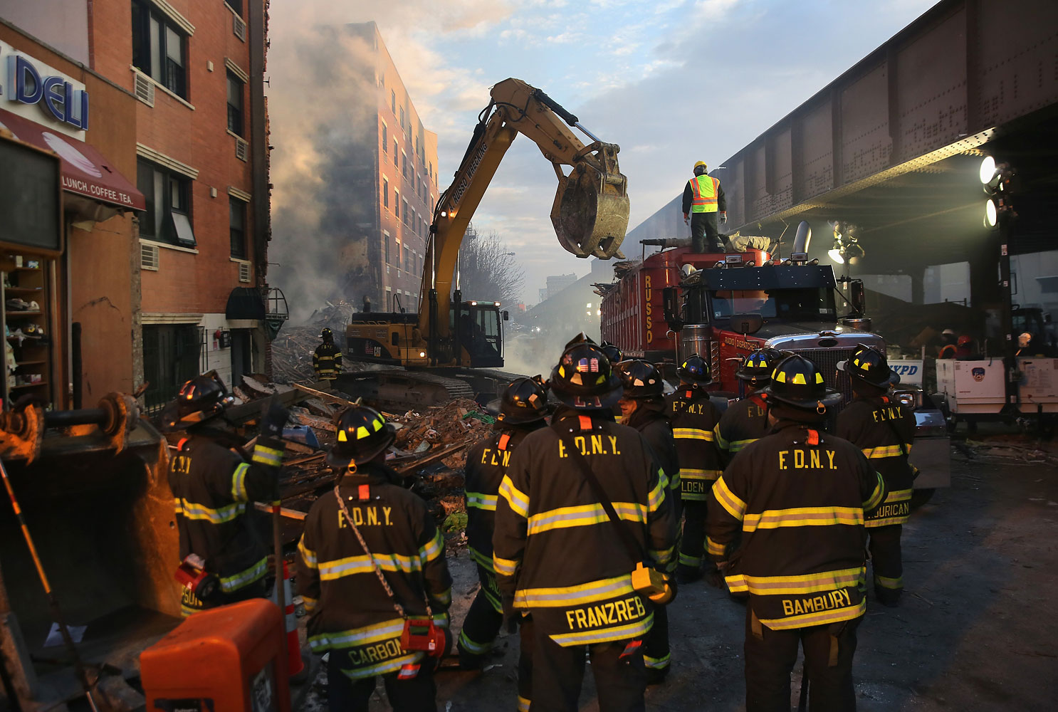 NEW YORK, NY - MARCH 13:  Firemen watch as work crews remove debris from the site of an explosion in East Harlem on March 13, 2014 in New York City. At least 7 people were killed, according to reports, in Wednesday's explosion which collapsed two buildings on Park Avenue at 116th Street. (John Moore—Getty Images)