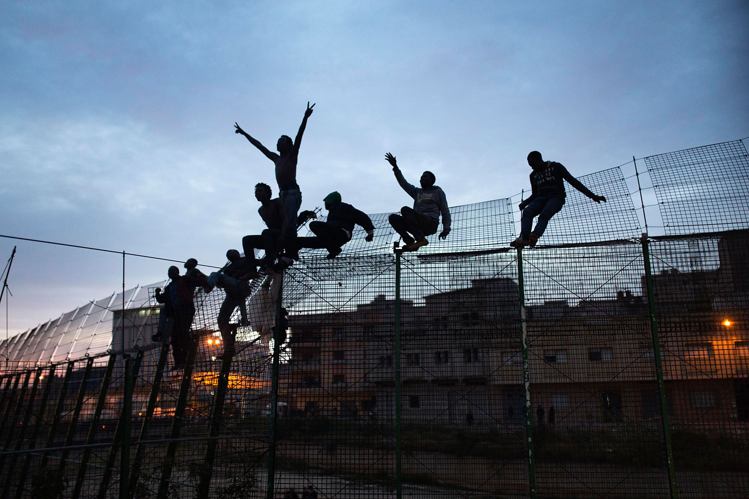 Sub-Saharan migrants climb over a metallic fence that divides Morocco and the Spanish enclave of Melilla, March 28, 2014.